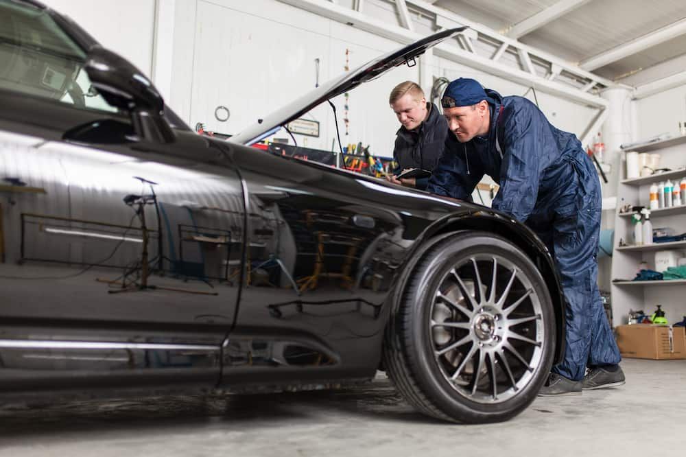 Two Mechanics Are Working On A Car In A Garage — Automotive Repair Centre In Garbutt, QLD
