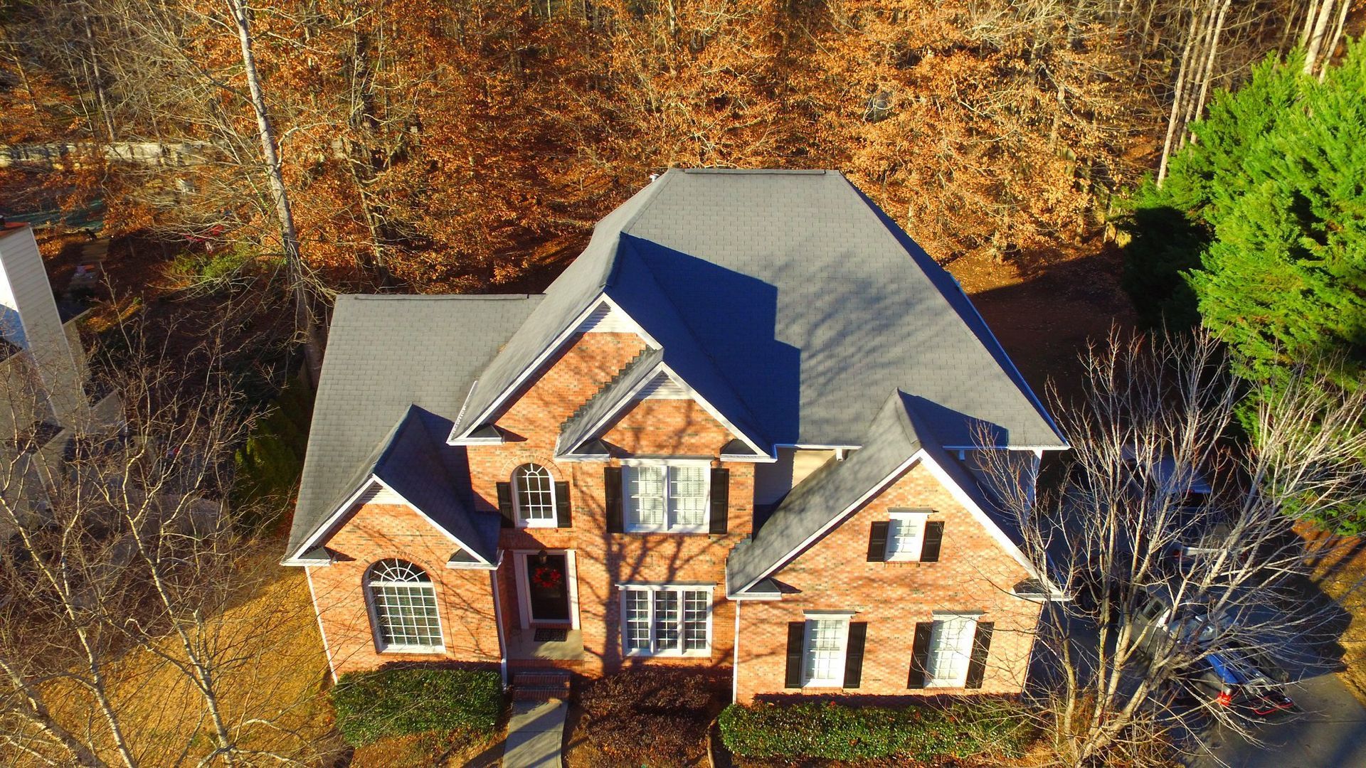 An aerial view of a large brick house surrounded by trees