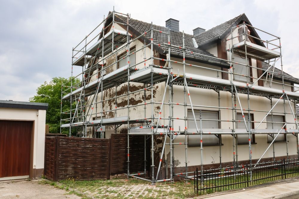 House exterior with scaffolding during renovation. Damaged paint visible.