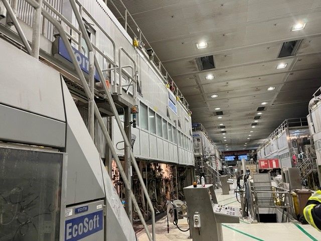 A man is standing in front of a large machine in a factory.