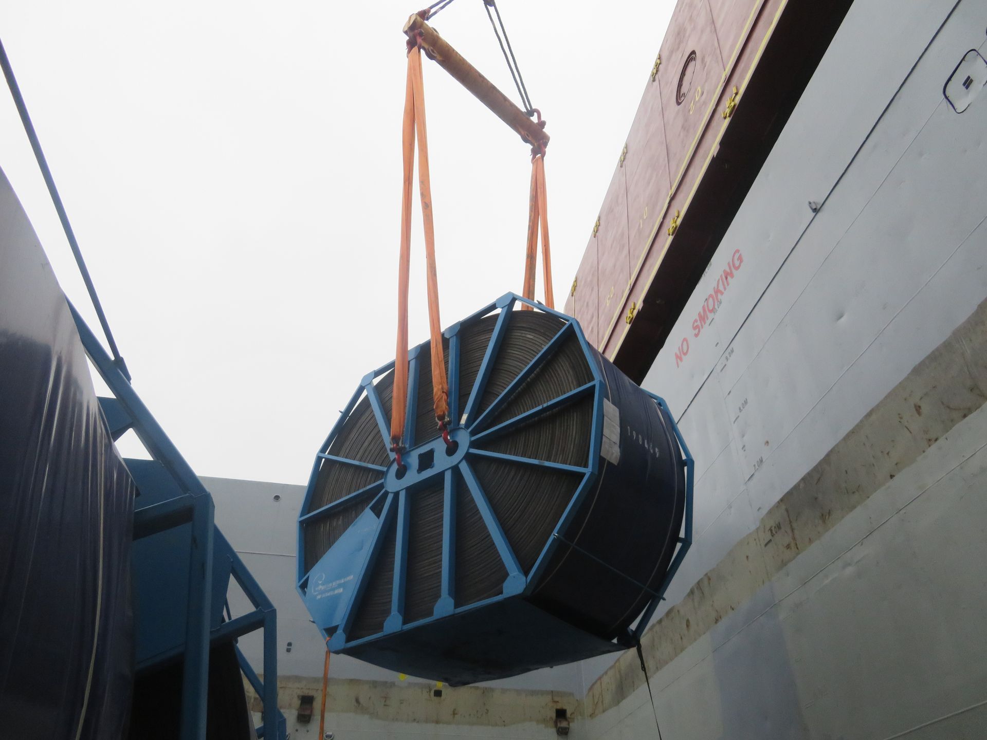 A large blue object is being lifted by a crane