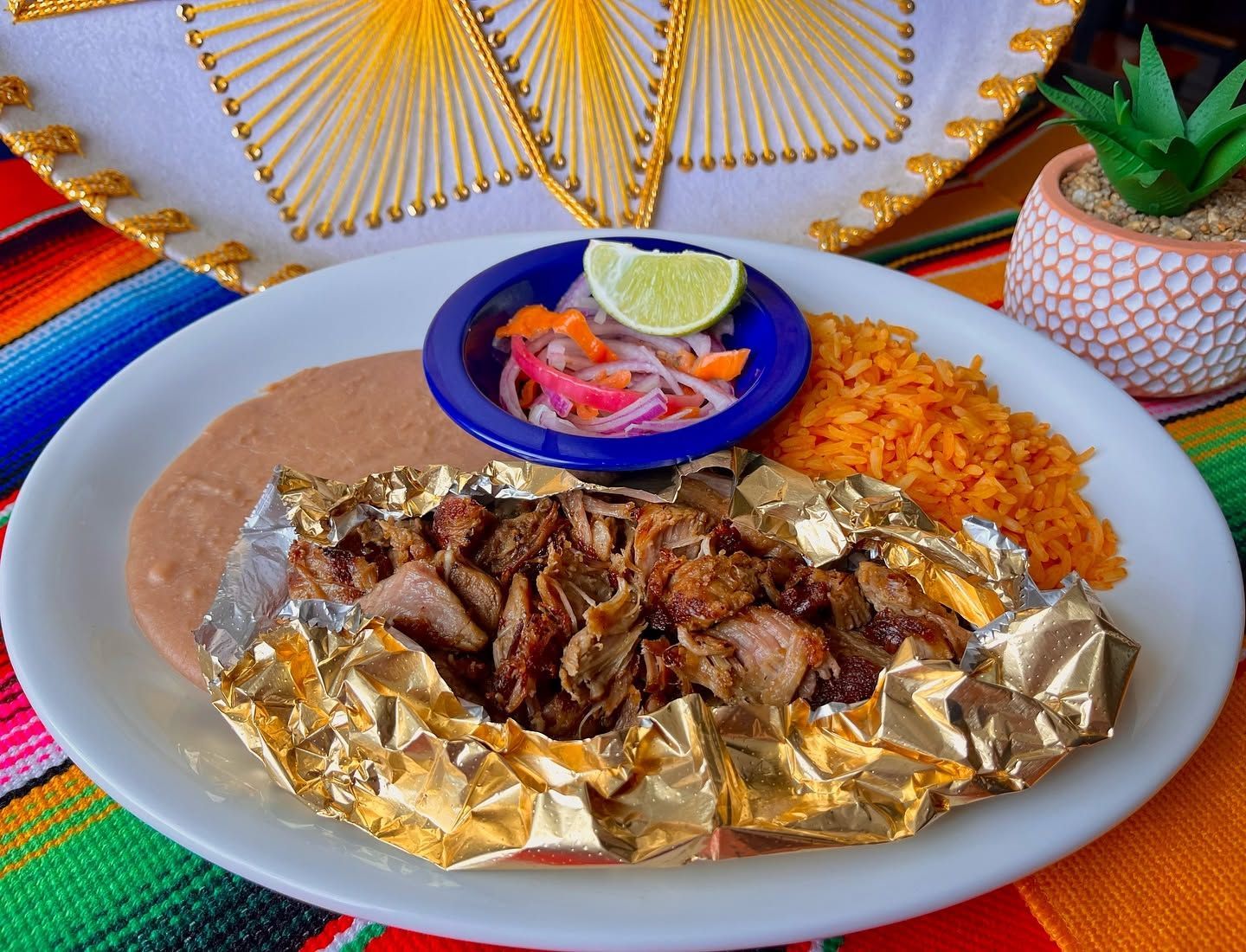 Plated grilled meat with rice, salad, and lime on a colorful table setting