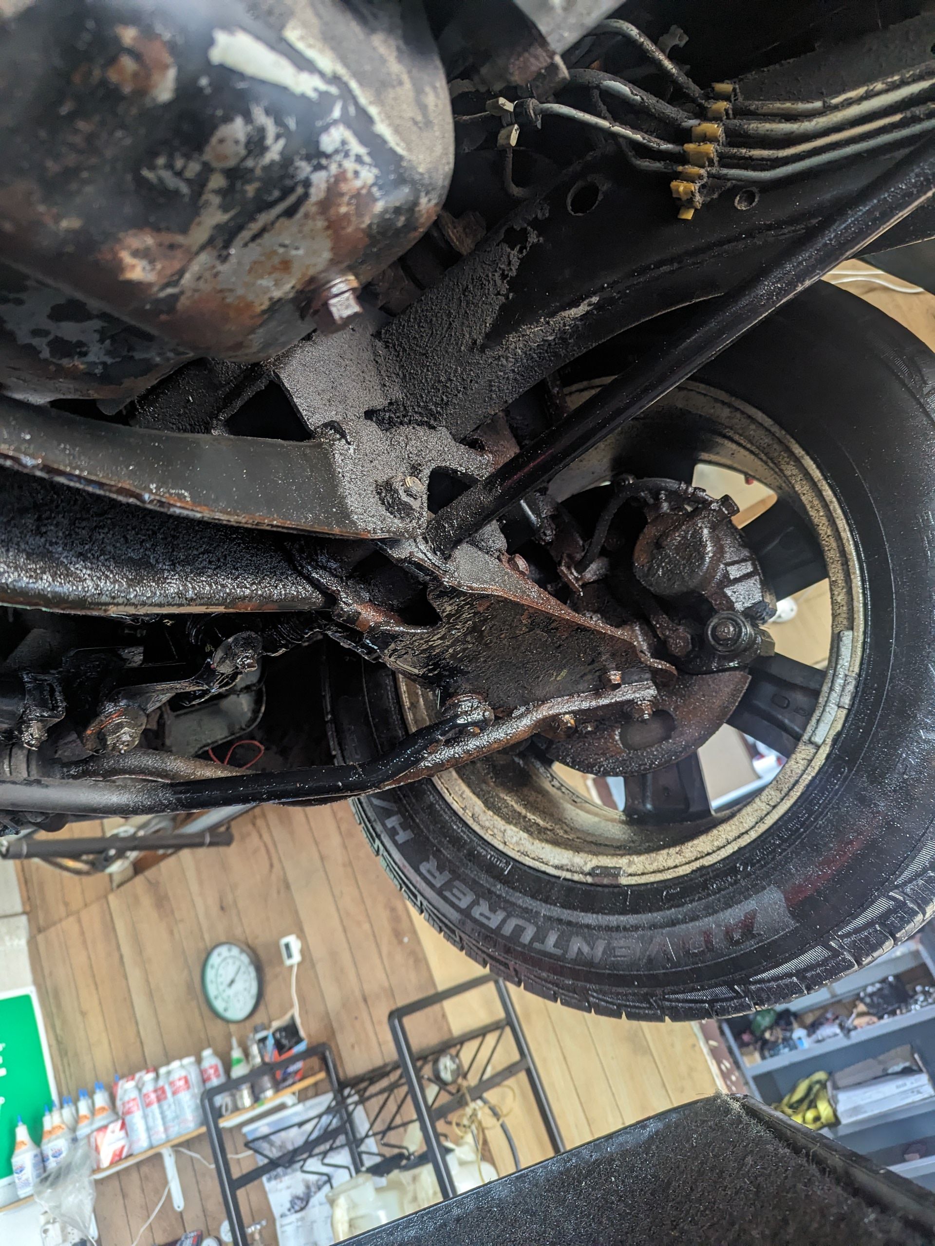 Upside-down close-up of a motorcycle’s rear wheel and engine, with metal components and a garage floor visible. | A & Z Auto Repair