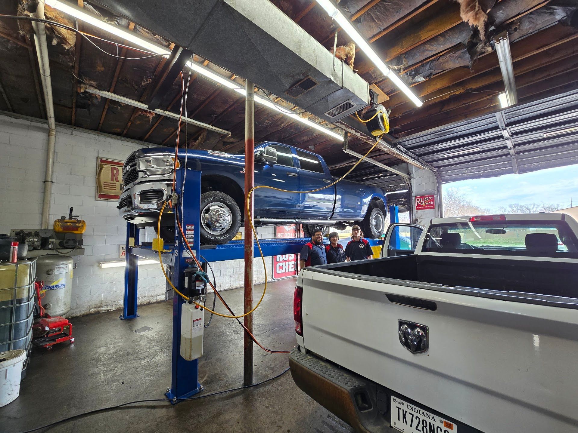 Auto repair shop with blue vehicle on a lift and white pickup truck in the foreground | A & Z Auto Repair