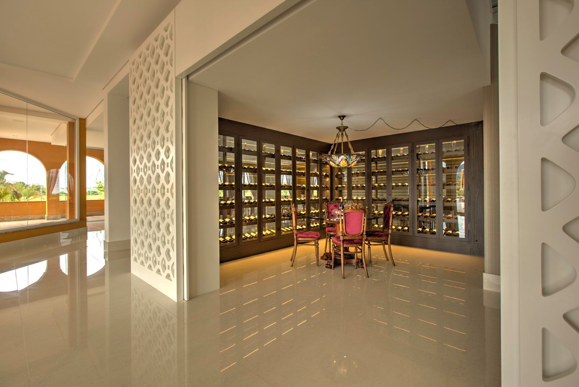 Sala de jantar elegante com depósito para vinhos, cadeiras rosa e um lustre.