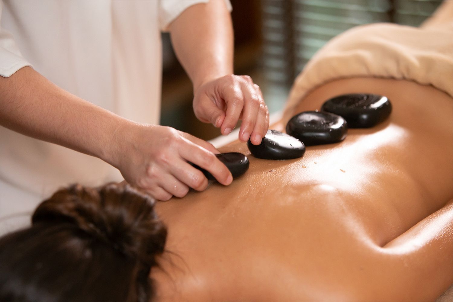 Pessoa recebendo massagem com pedras quentes nas costas.