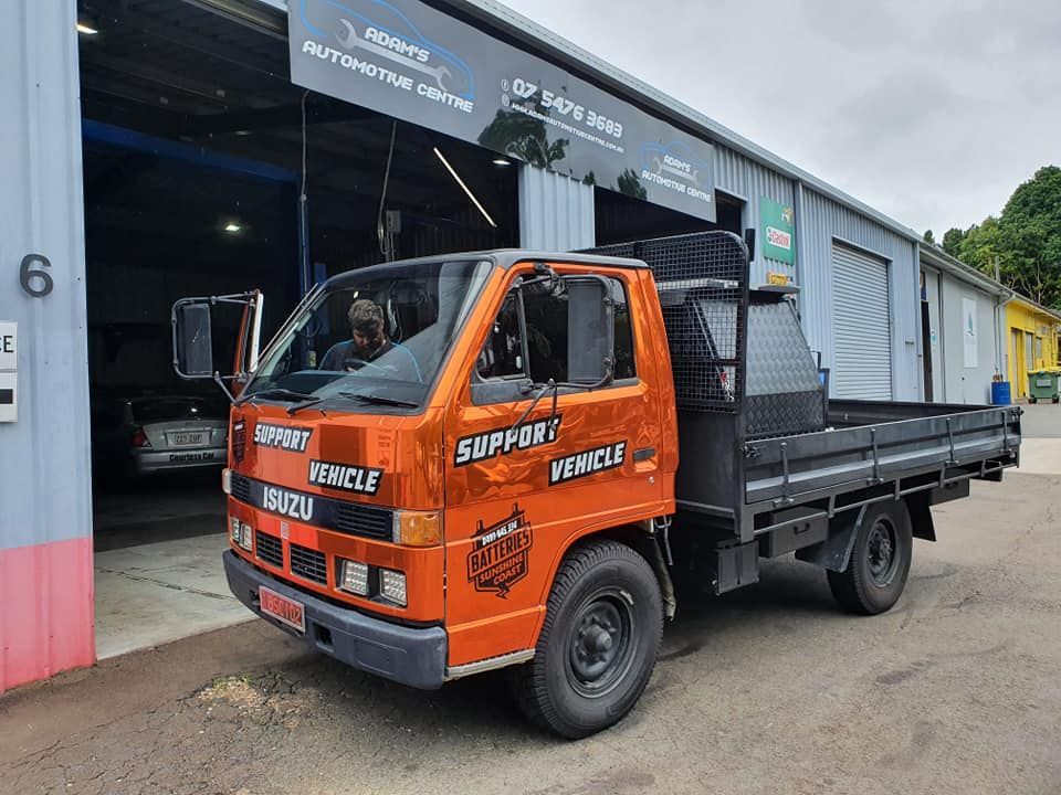 Orange Isuzu Support Vehicle parked outside a garage, with a driver visible.  — Adam's Automotive Centre in Nambour, QLD