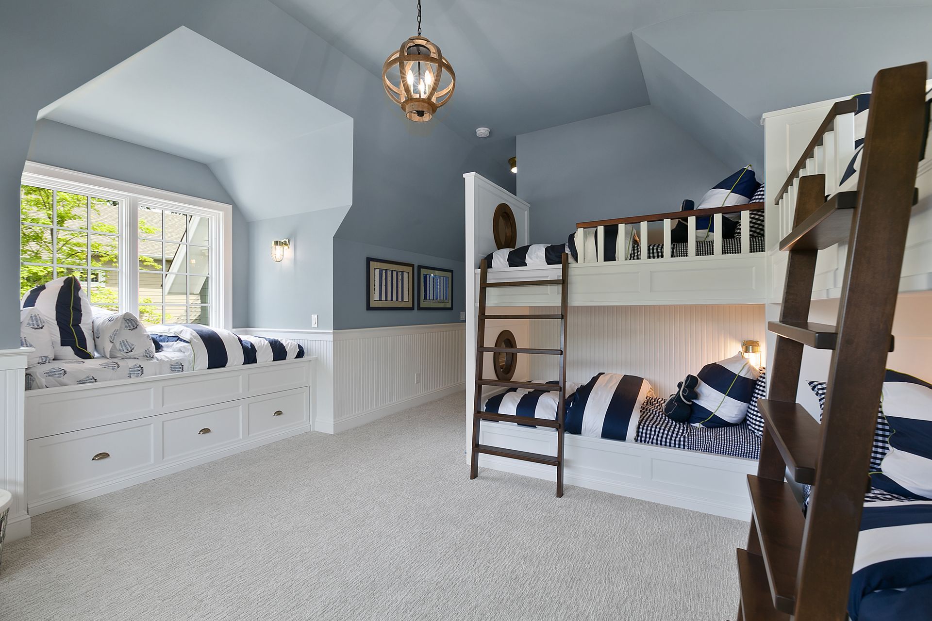 Blue and white nautical themed bunk room with window seat and wooden ladder.