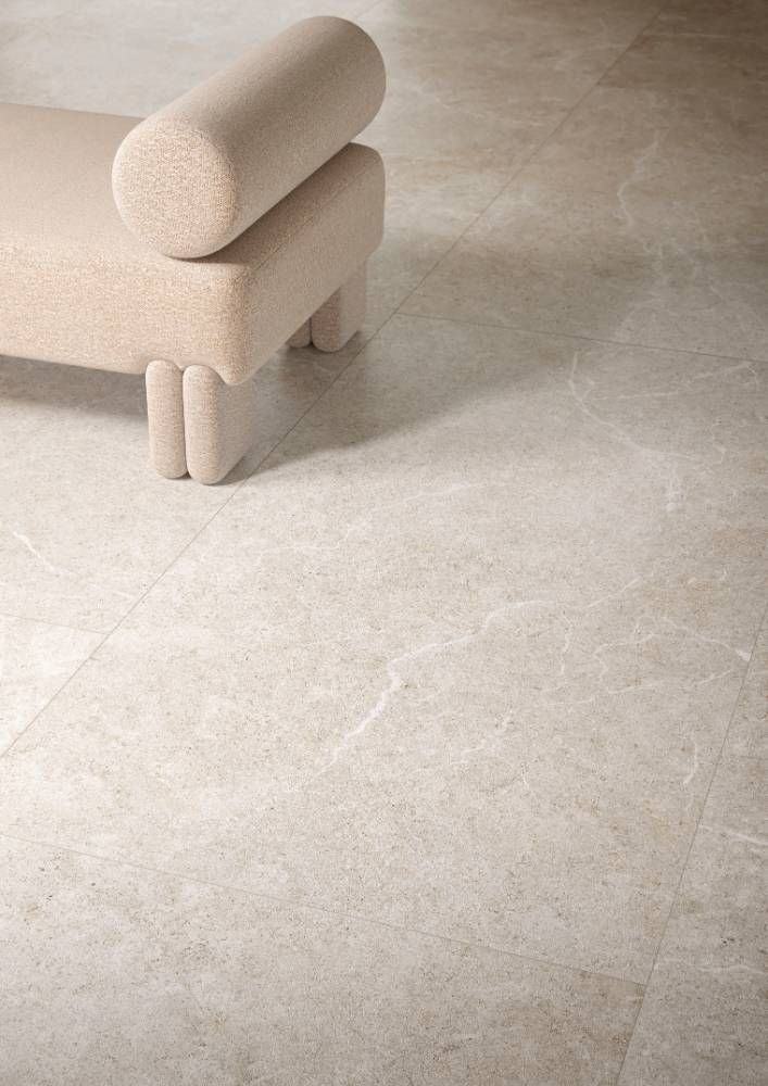 A White Chair is Sitting on a Tiled Floor Next to a White Couch — Tileflair in Mitchell, ACT

