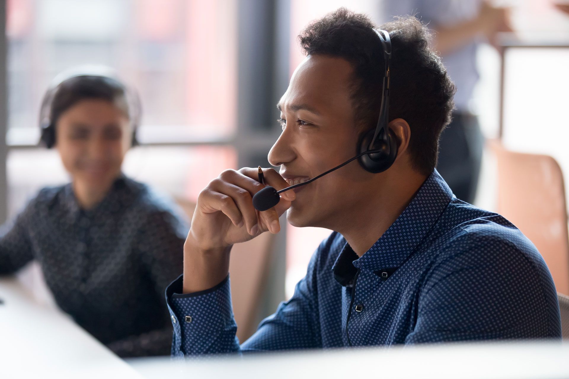 a man wearing a headset is sitting at a desk in front of a computer