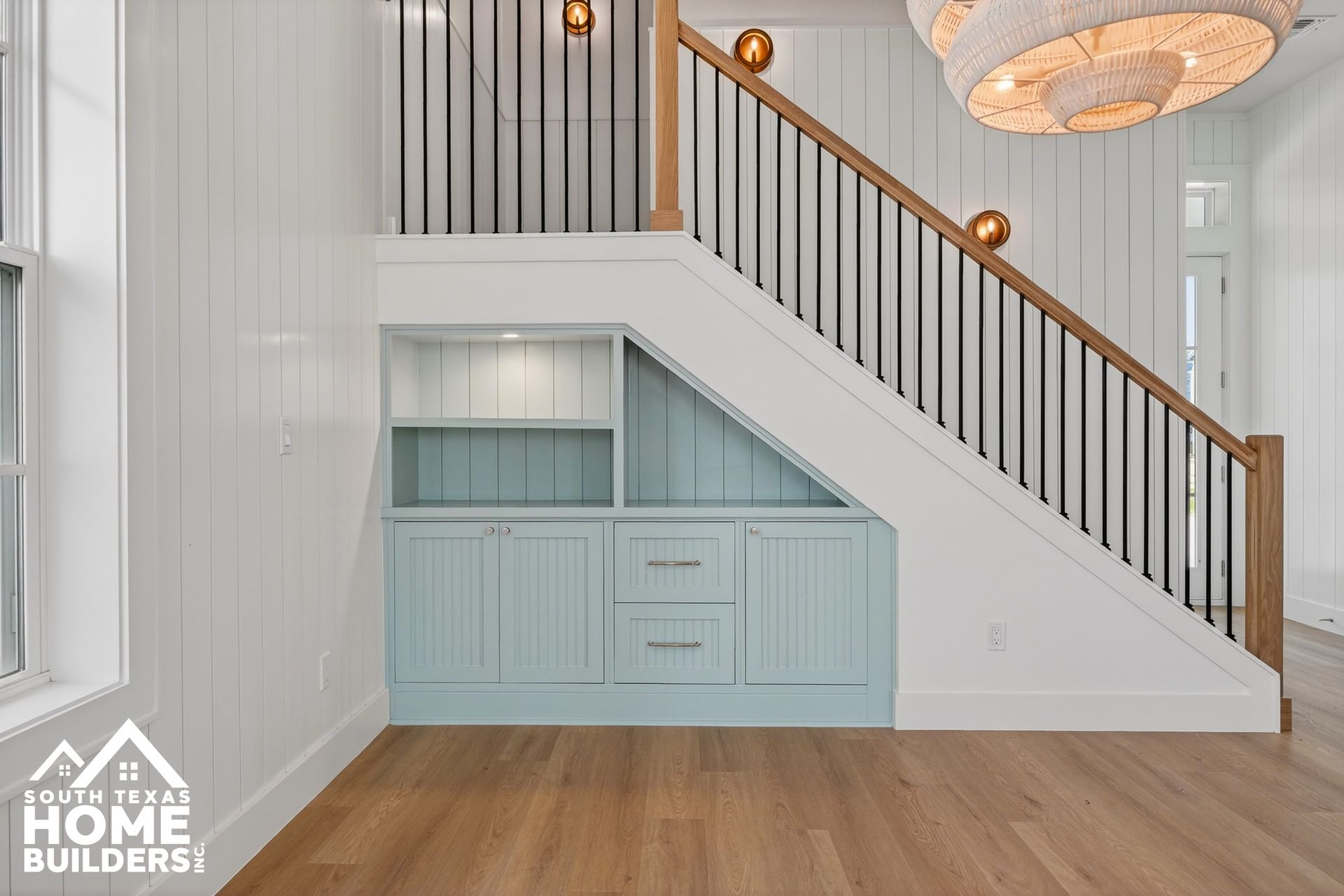 Built-in under-stair cabinetry with pale blue drawers in a bright modern entryway