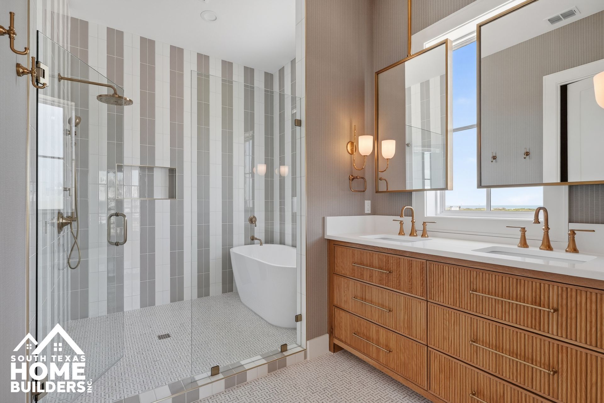 Modern bathroom with glass shower, freestanding tub, and wood double vanity by a large window