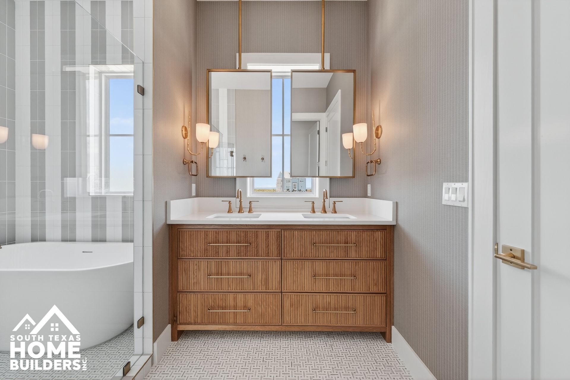 Modern bathroom vanity with wood cabinet, white countertop, wall sconces, and striped wallpaper.