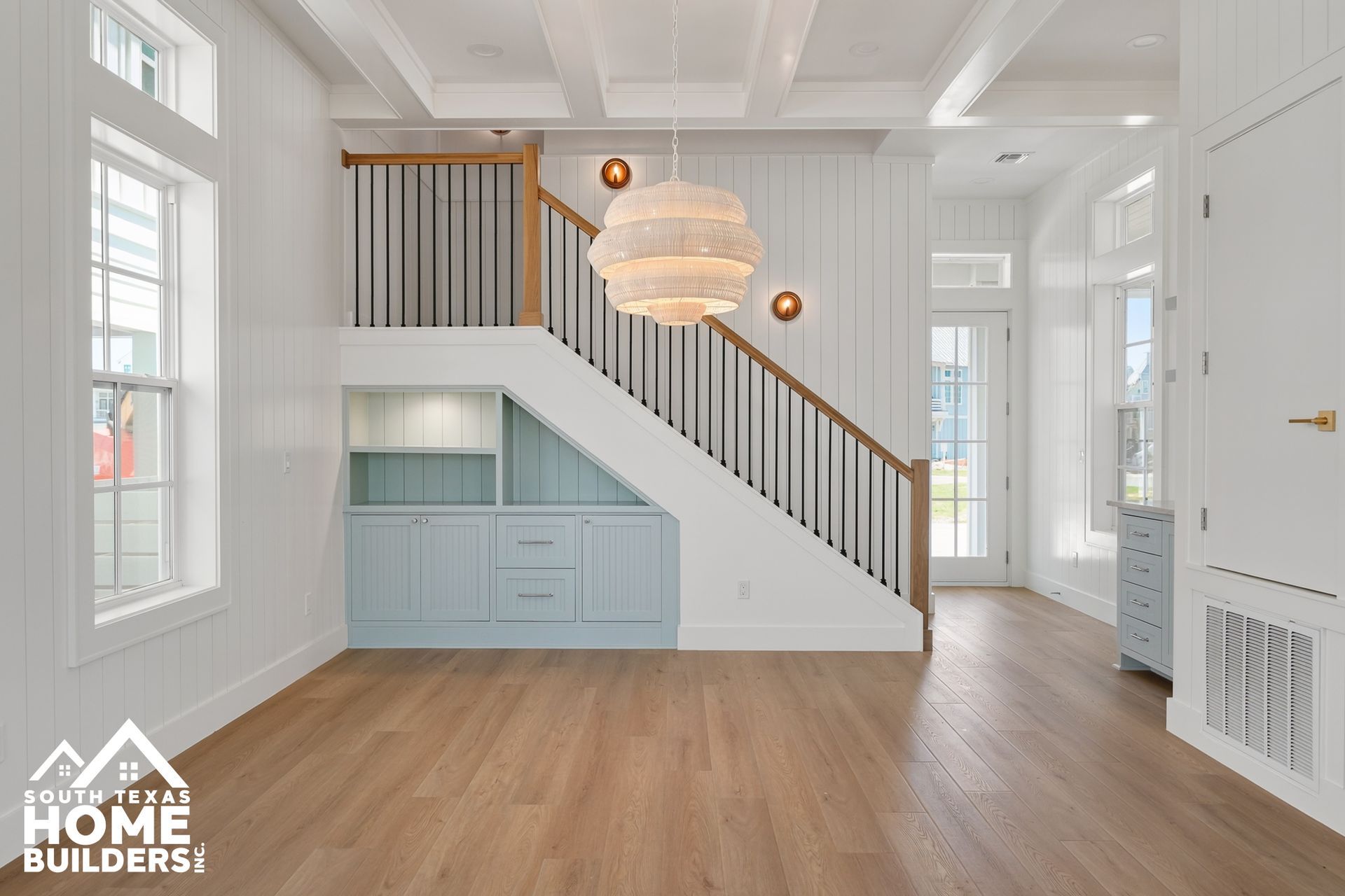 Bright white foyer with staircase, wood floors, built-in cabinetry, and a chandelier
