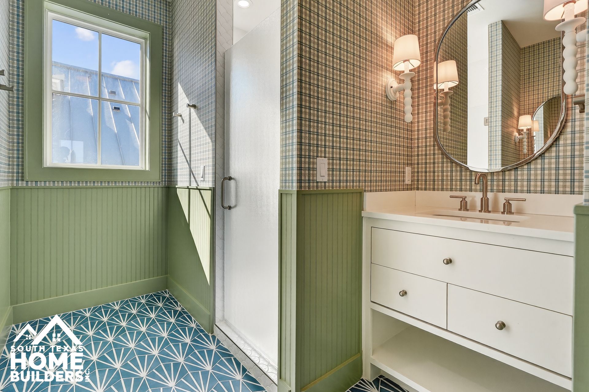 Green bathroom with blue patterned floor, white vanity, shower, and windowed nook
