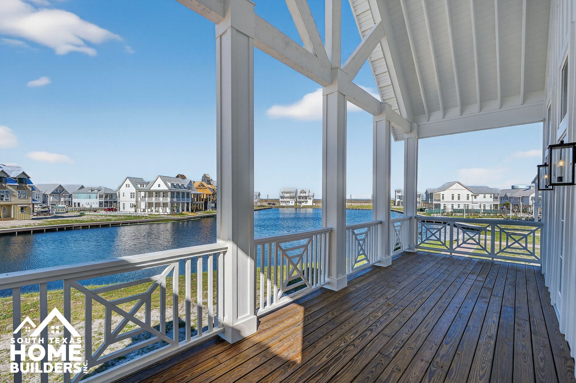 Covered wooden balcony overlooking waterfront homes and blue water on a sunny day