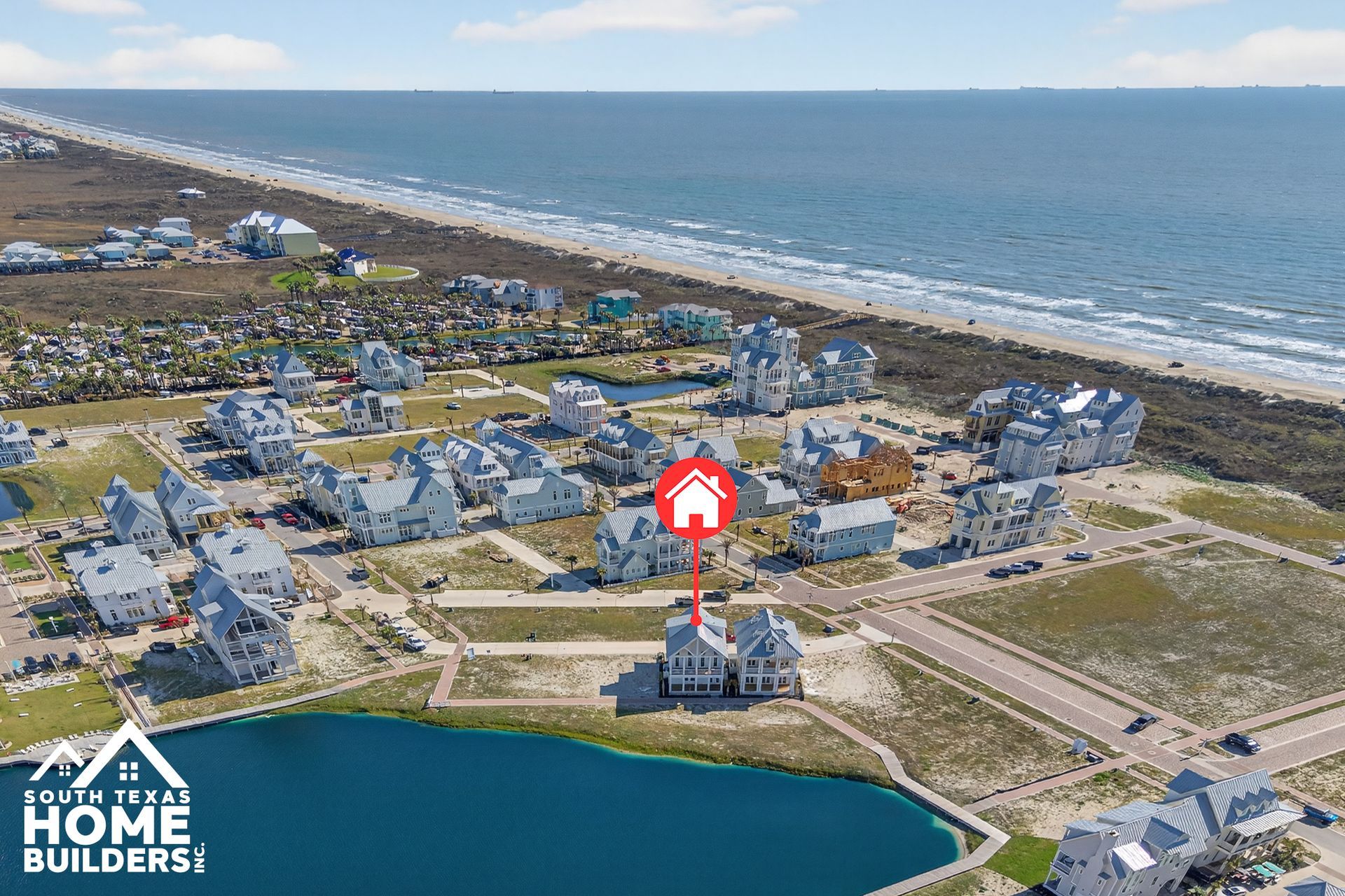 Aerial view of a coastal neighborhood with ocean, houses, roads, and a highlighted home near the water