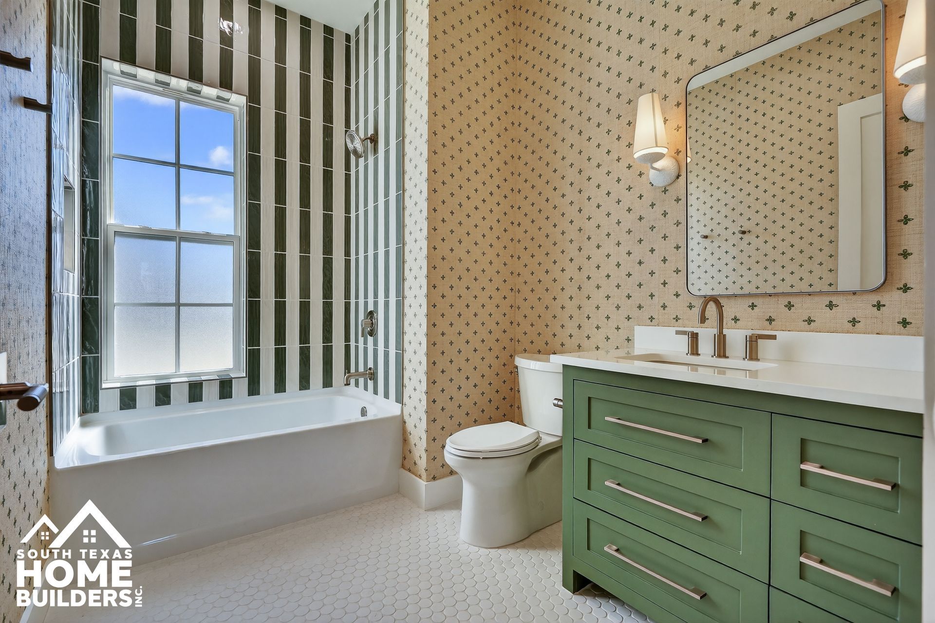 Bathroom with green vanity, patterned wallpaper, white tub, and striped window wall treatment.