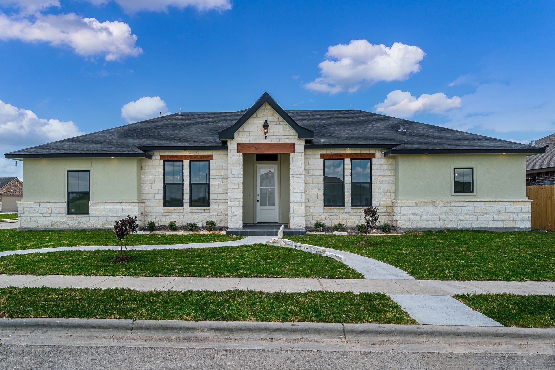 The front of a house with a lot of windows and a walkway leading to it.