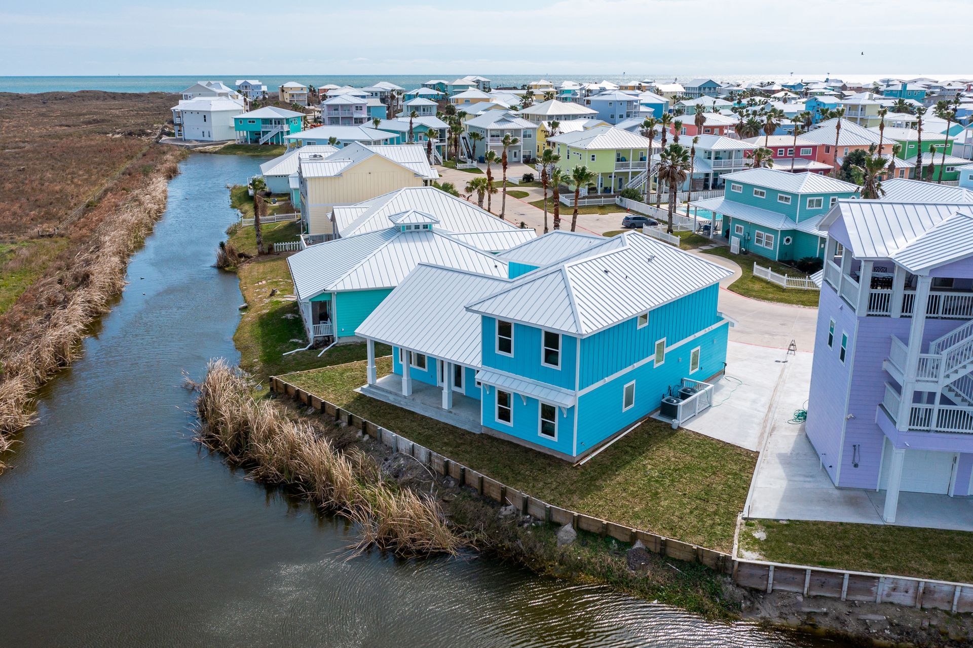 An aerial view of a blue house next to a river