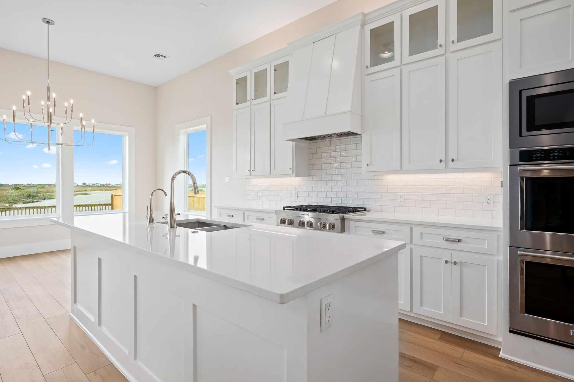 A kitchen with white cabinets , stainless steel appliances , and a large island.