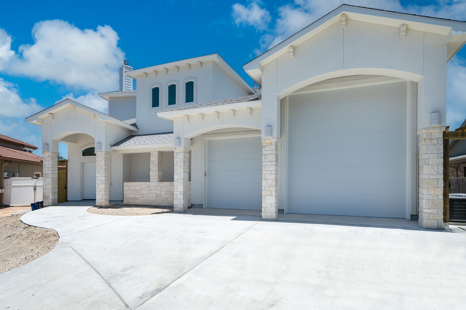 A white house with three garage doors and a concrete driveway