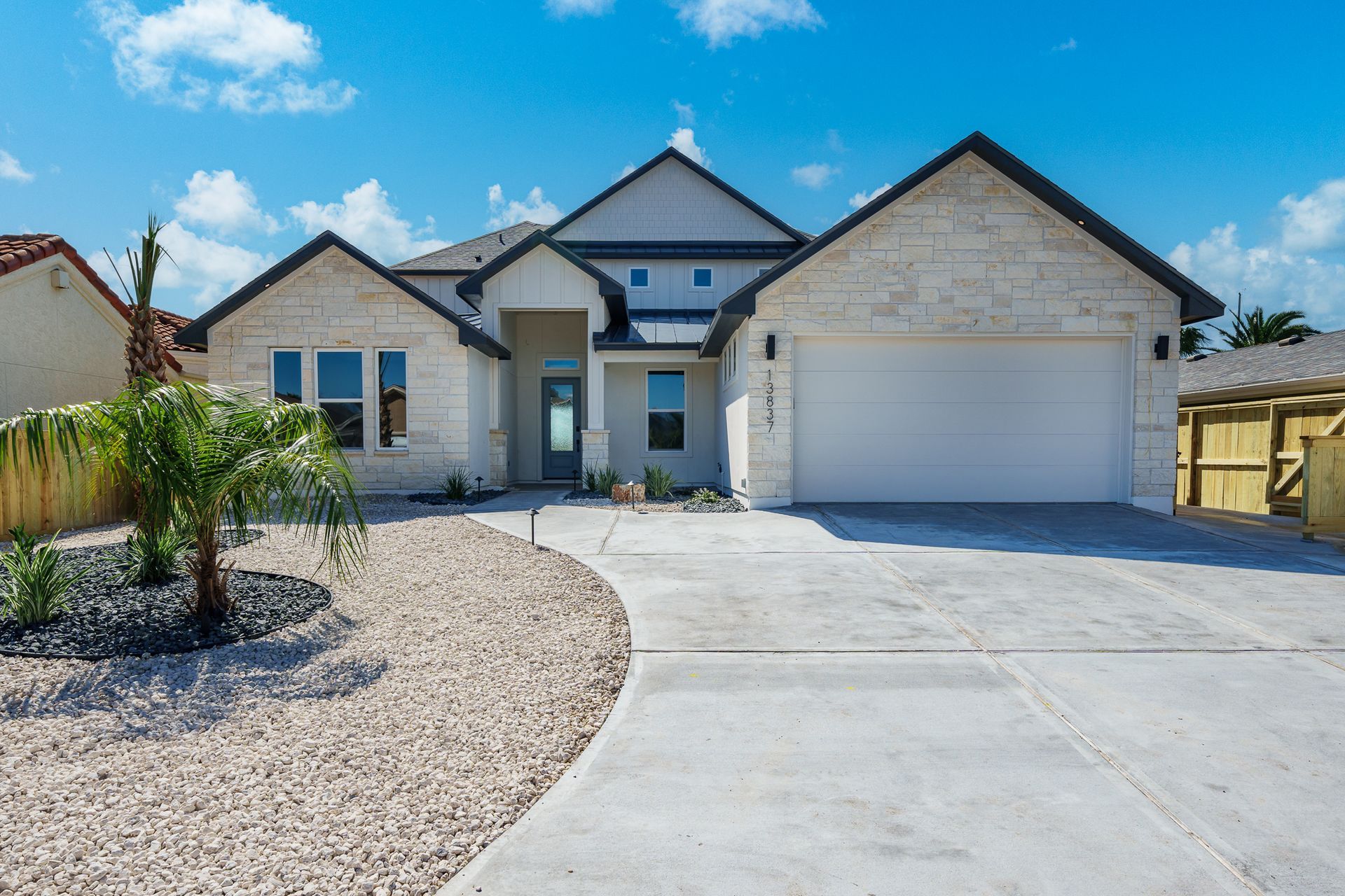A large white house with a white garage door and a gravel driveway.