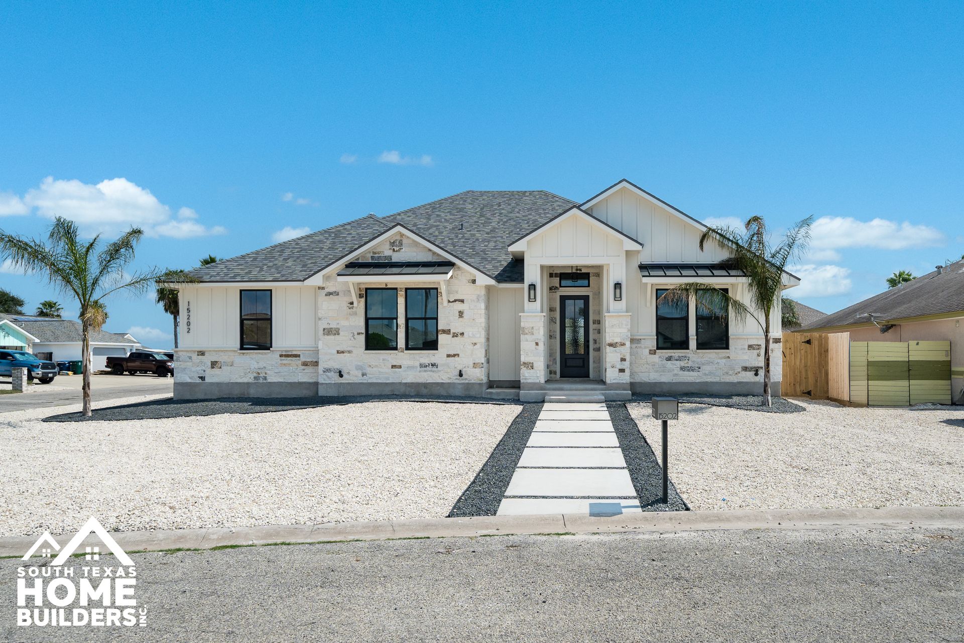 Modern one-story house with stone facade, gray roof, and walkway leading to the front door.