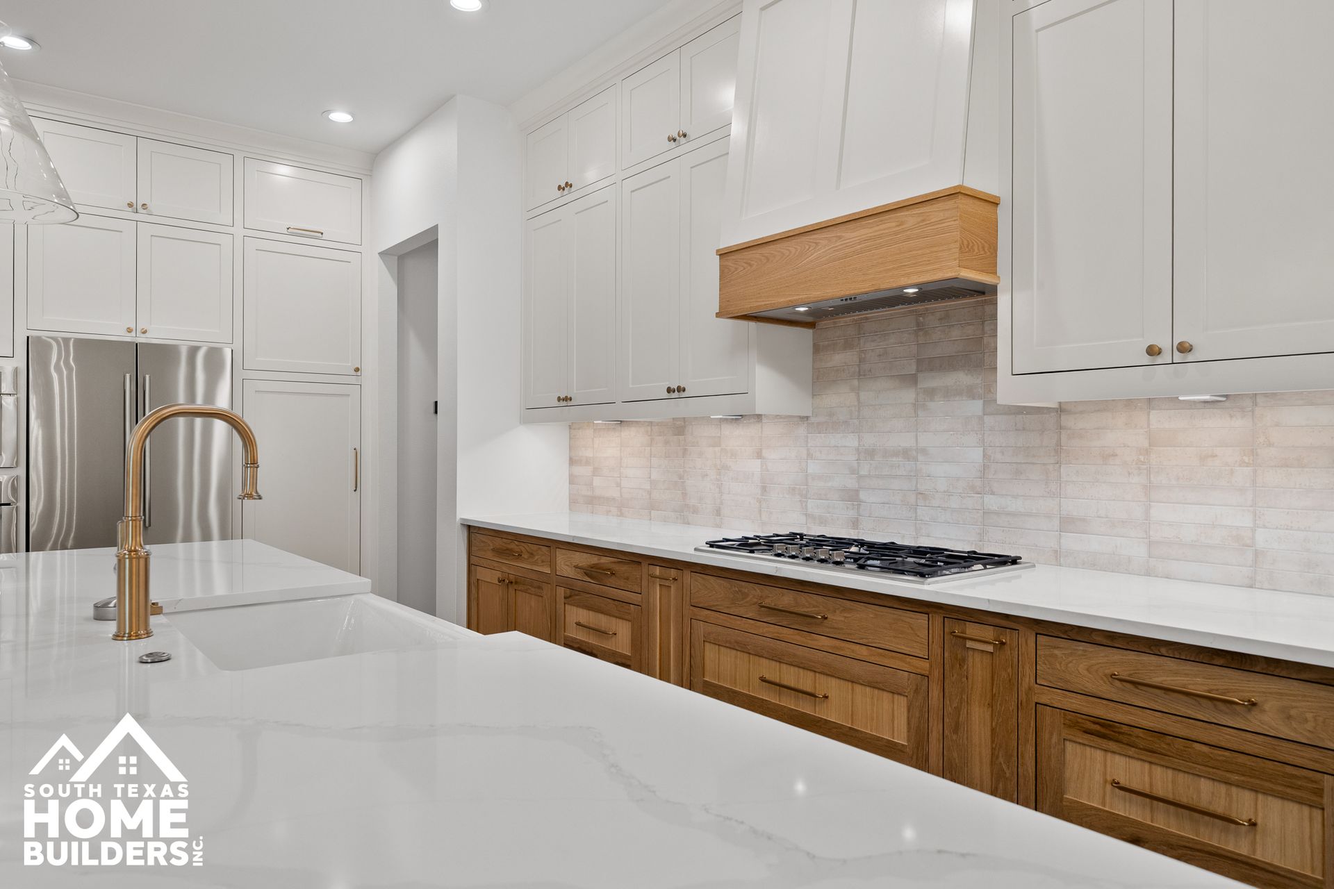 Modern kitchen with white upper cabinets, wood lower cabinets, and a white countertop.