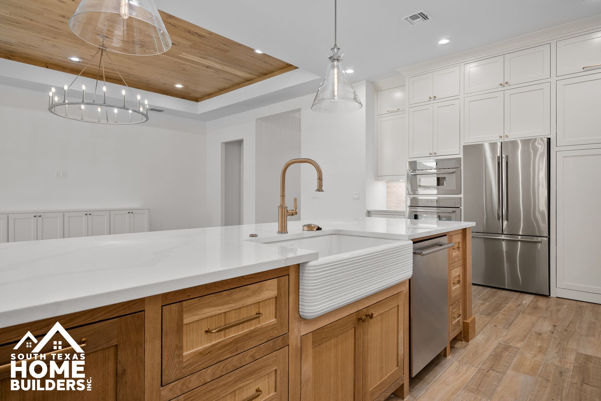 Modern kitchen with wooden island, white countertops, stainless steel appliances, and wood ceiling.