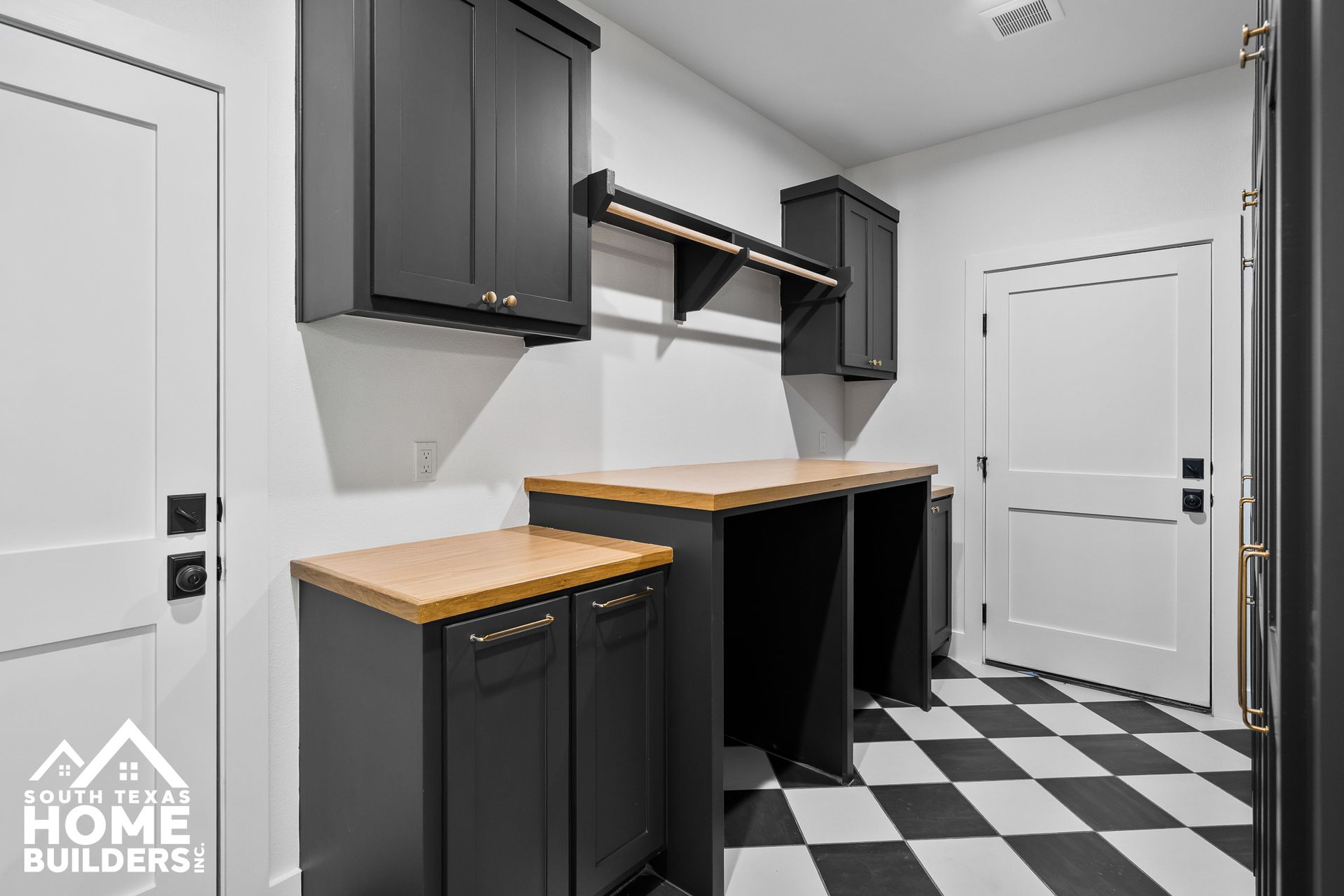 Black and white laundry room with cabinets, counter, hanging rod, and checkered floor.