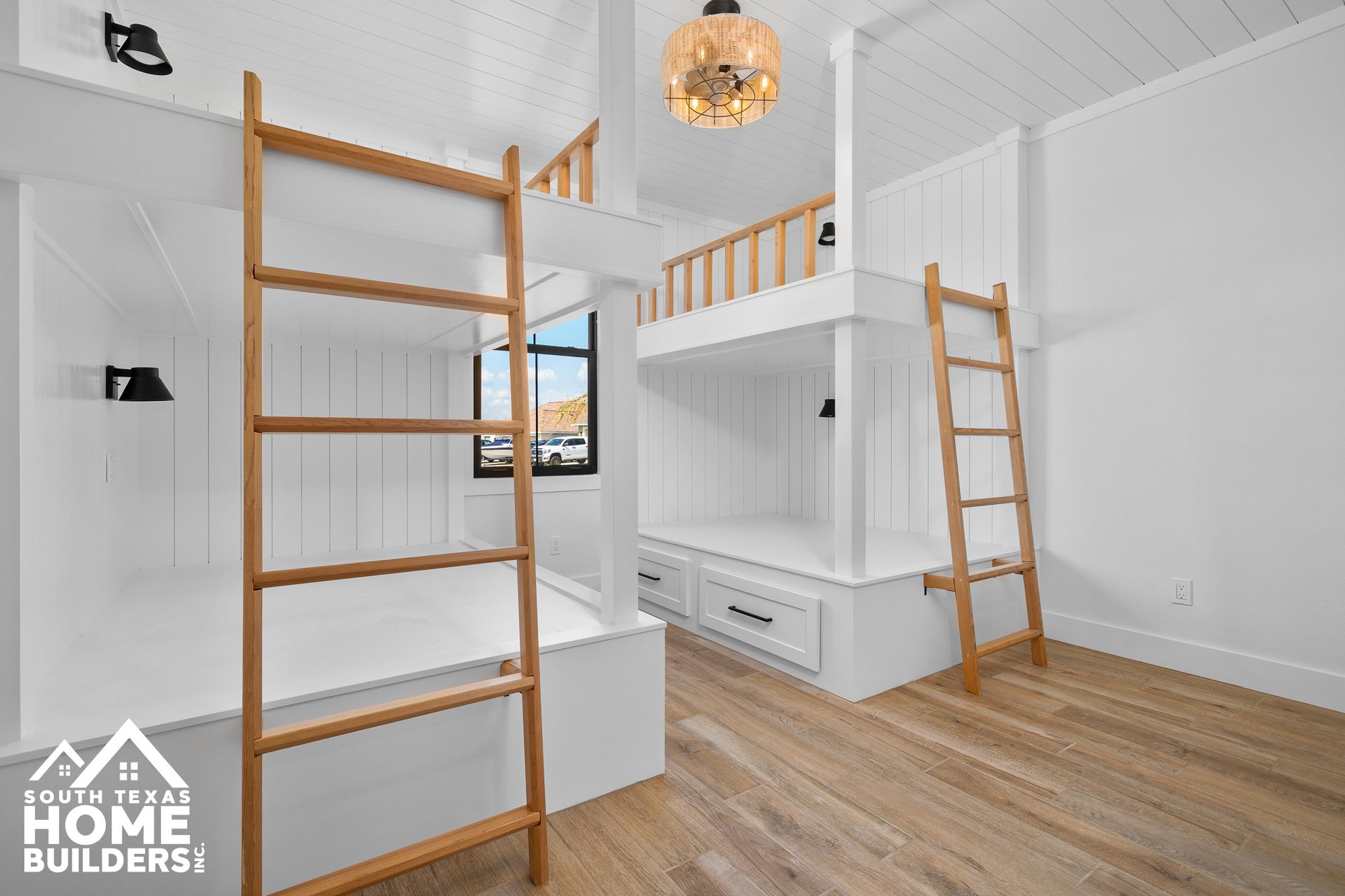 Modern white bunk bed with wooden ladders, built-in storage, and a loft area in a bright room.