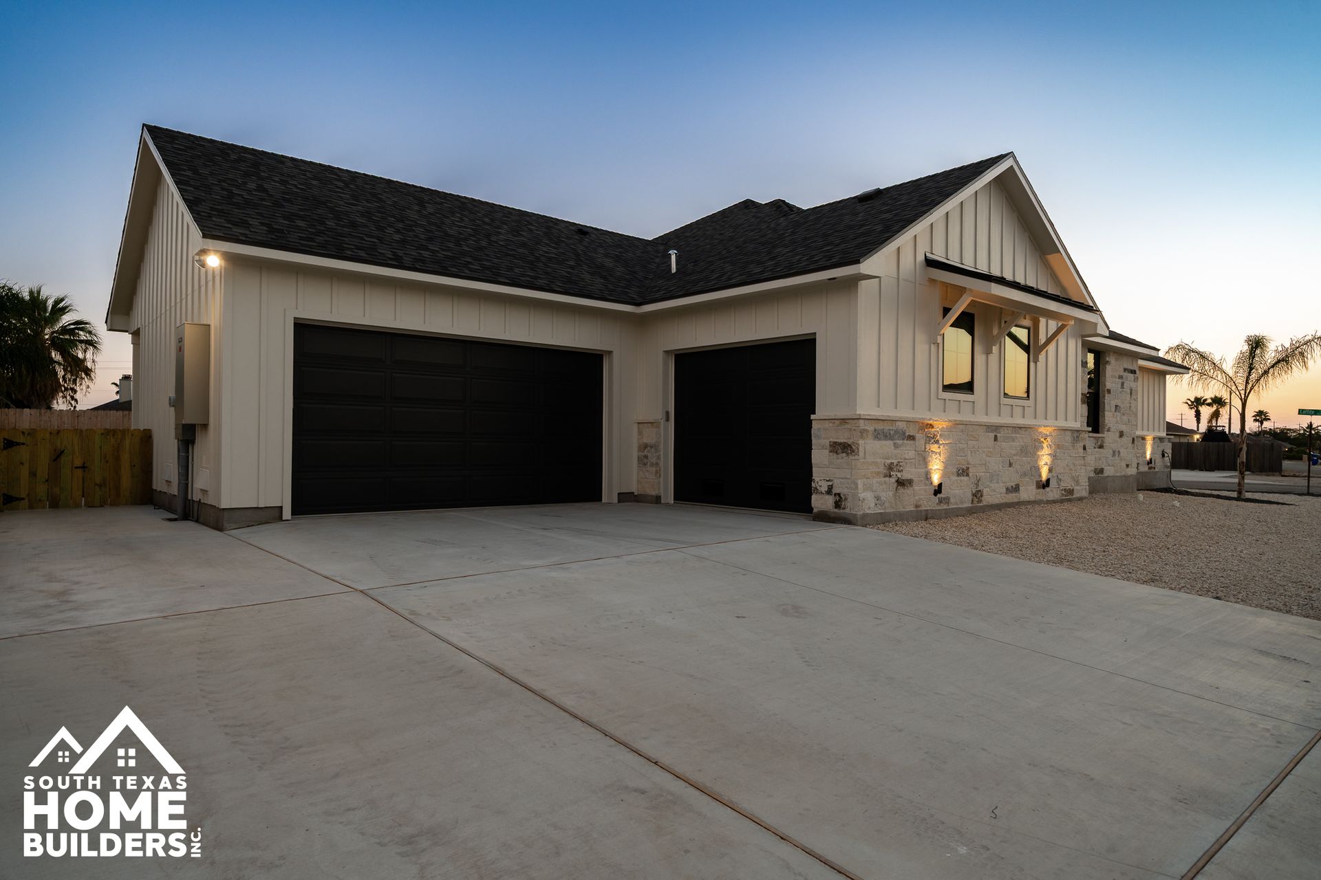 Modern home with black garage doors, white siding, and a concrete driveway.