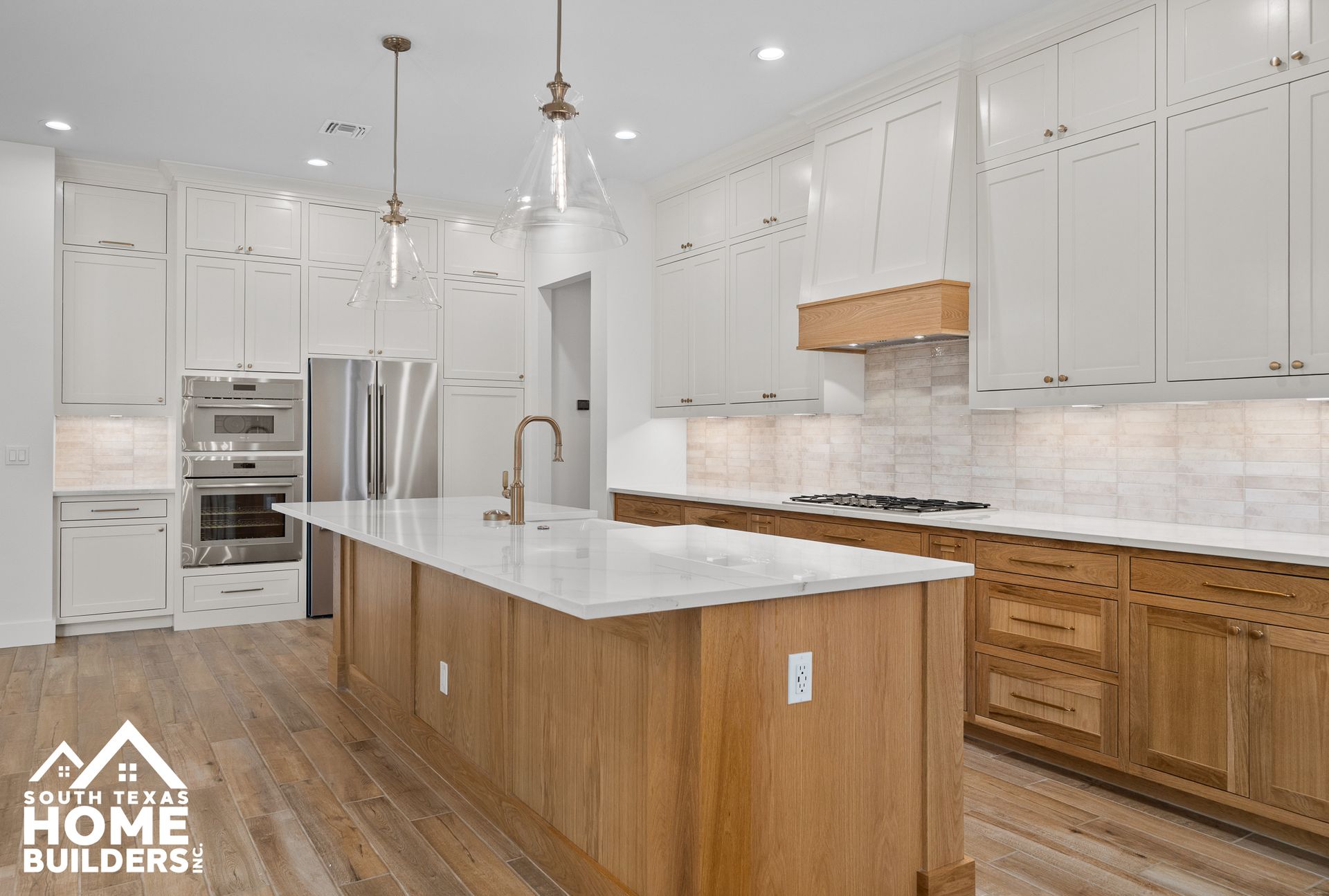 Modern kitchen with white upper cabinets, wood island and lower cabinets, stainless steel appliances.