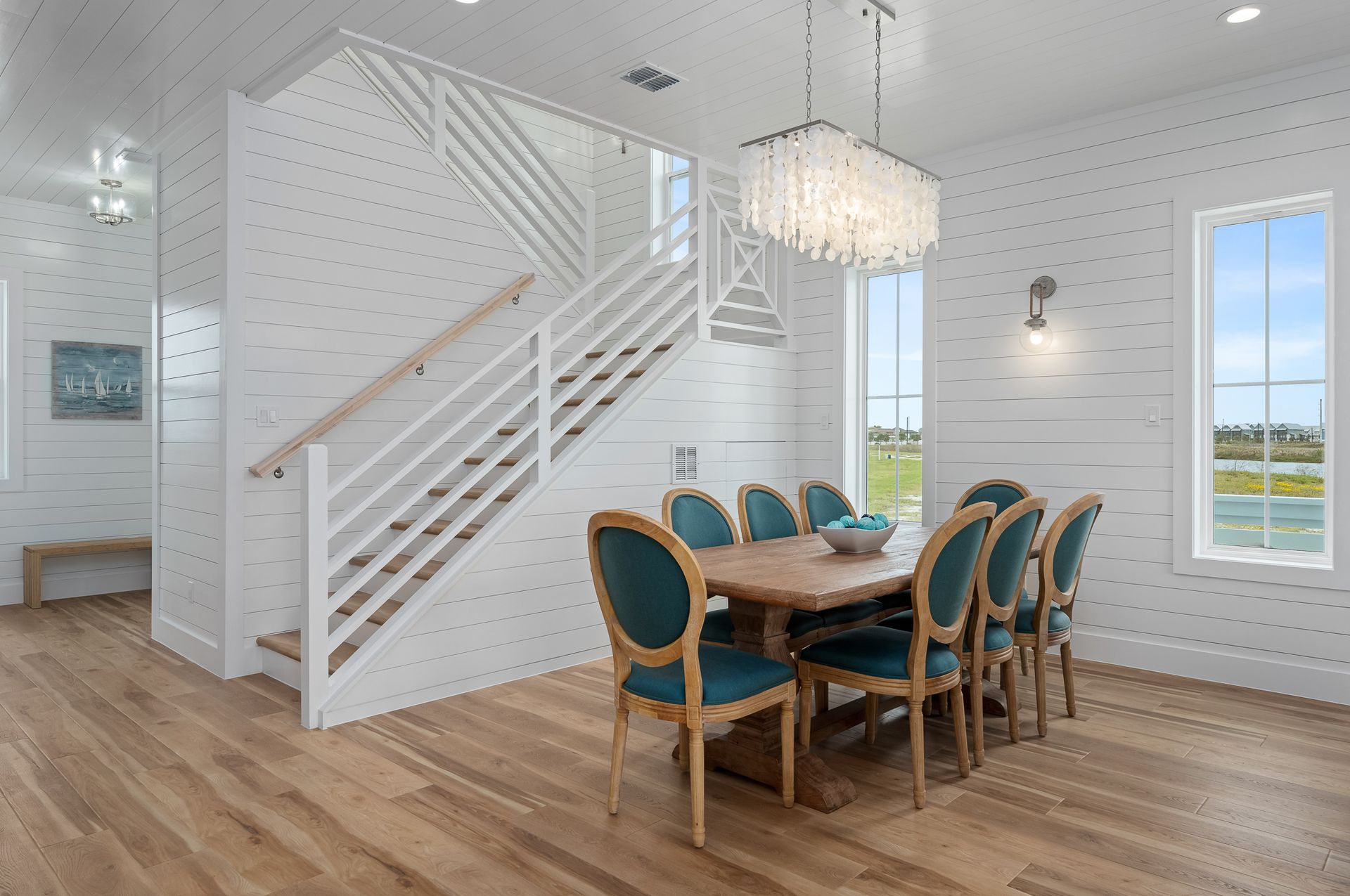 A dining room with a table and chairs and stairs.