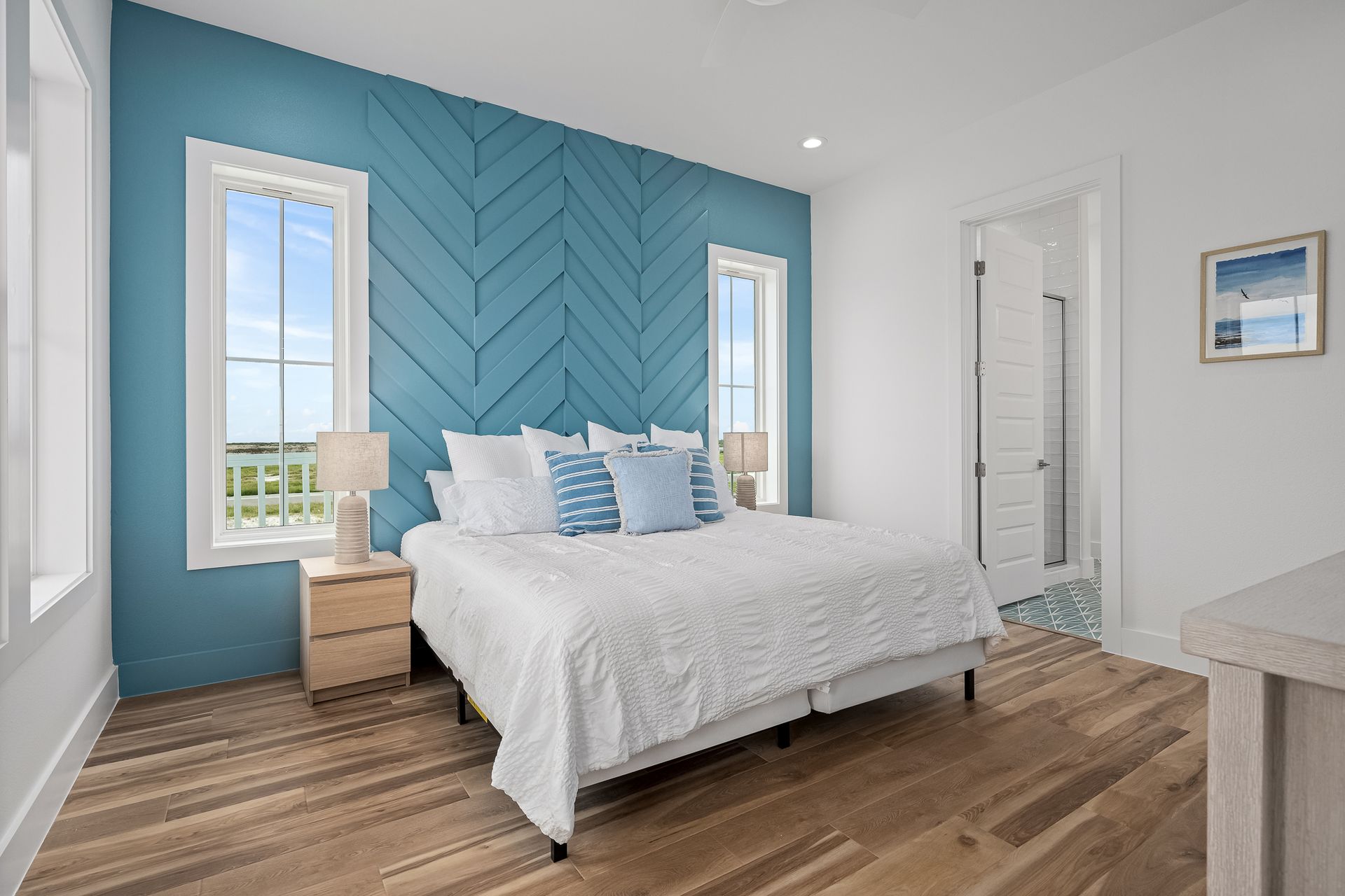 A bedroom with a king size bed , two windows and a blue wall.