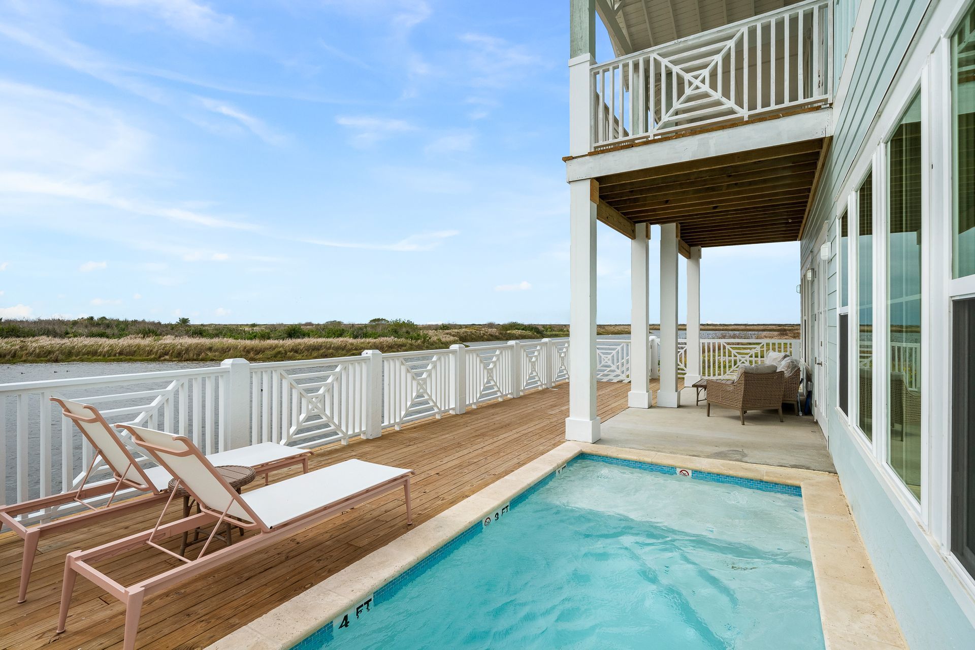 There is a large swimming pool in the backyard of a house.