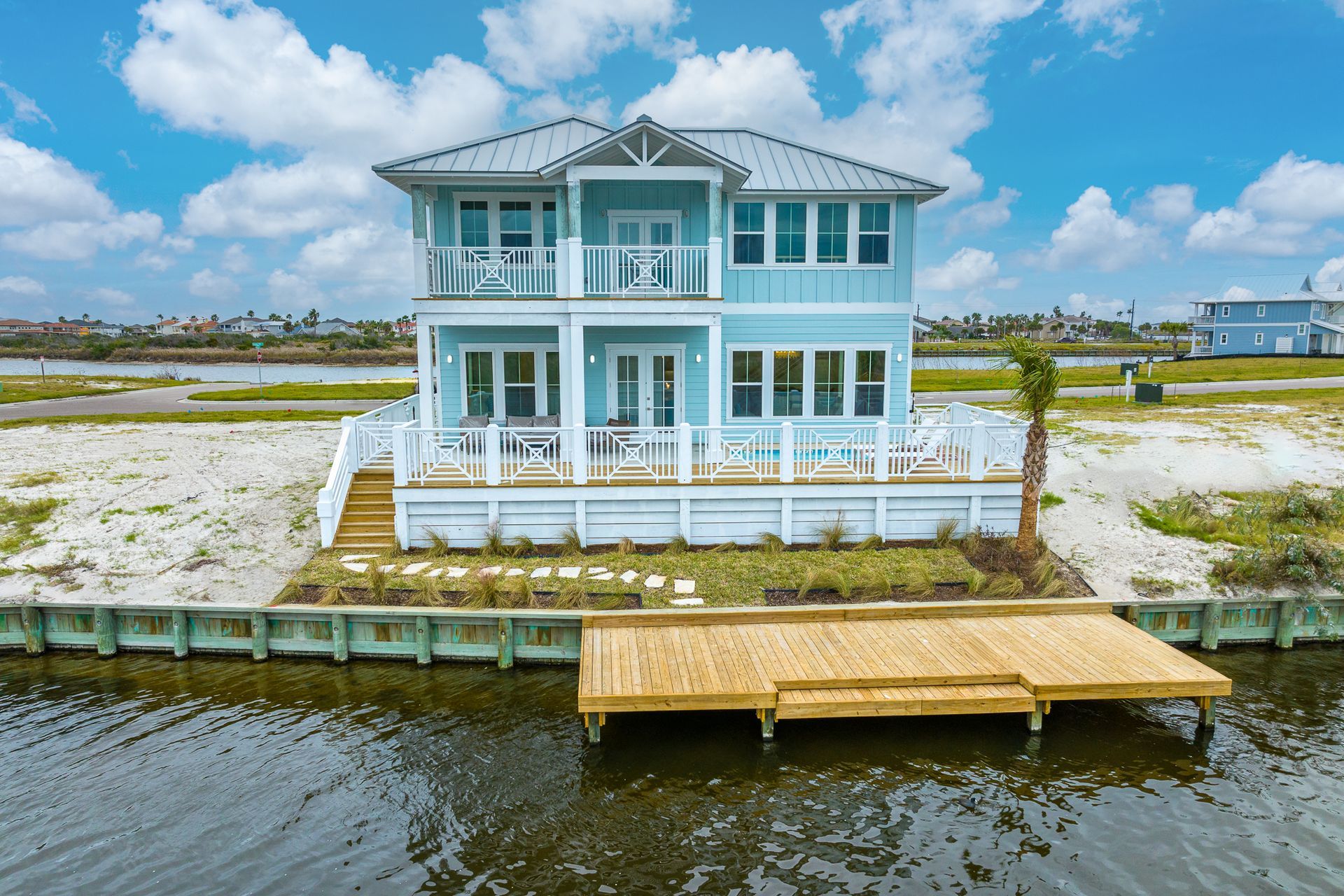 A large house is sitting on top of a small island in the middle of a body of water.