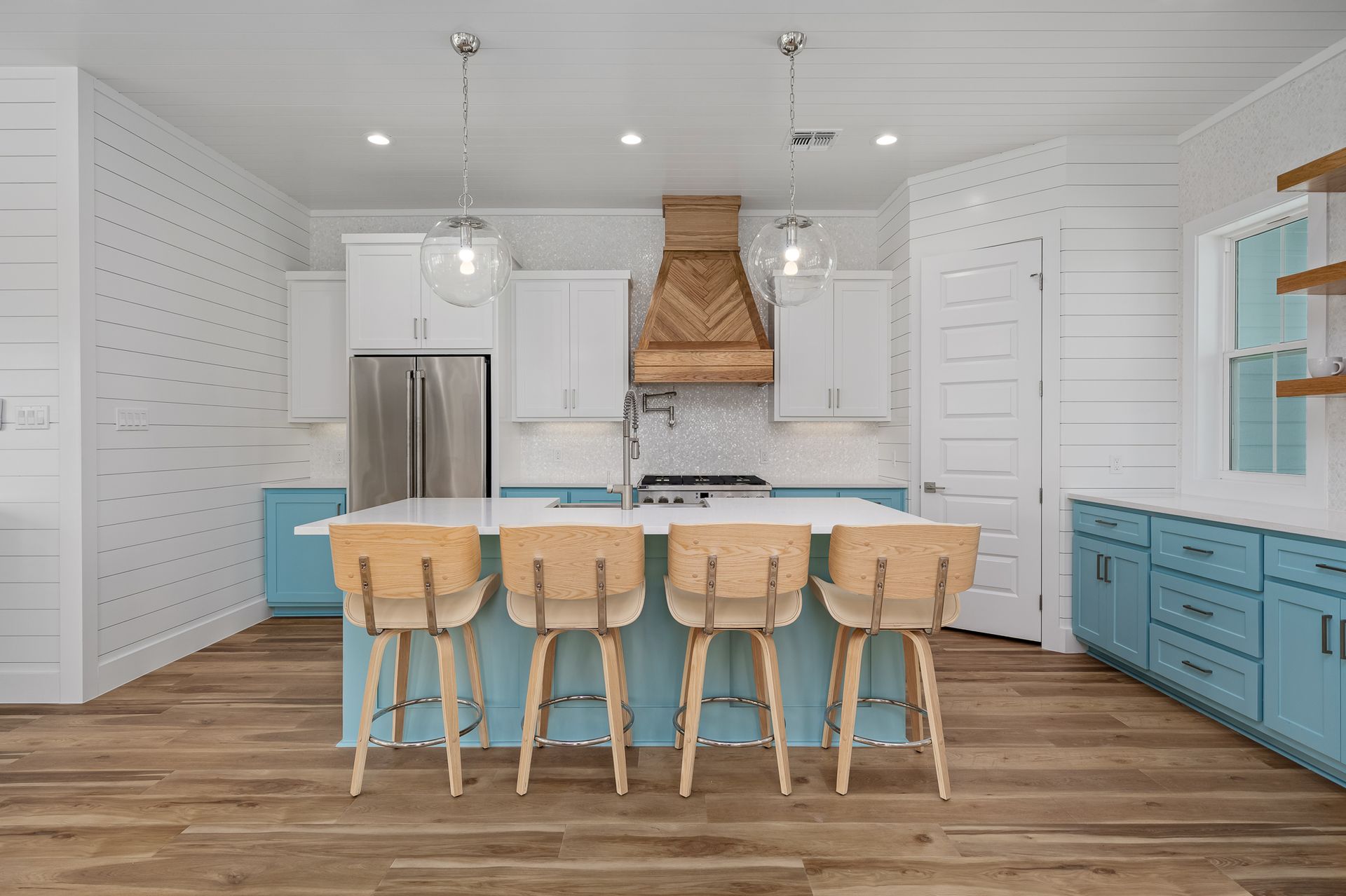 A kitchen with blue cabinets , white cabinets , wooden floors and a large island.