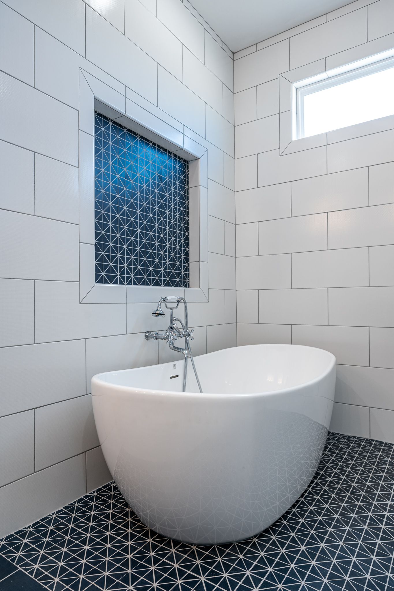 A white bathtub in a bathroom with black and white tiles