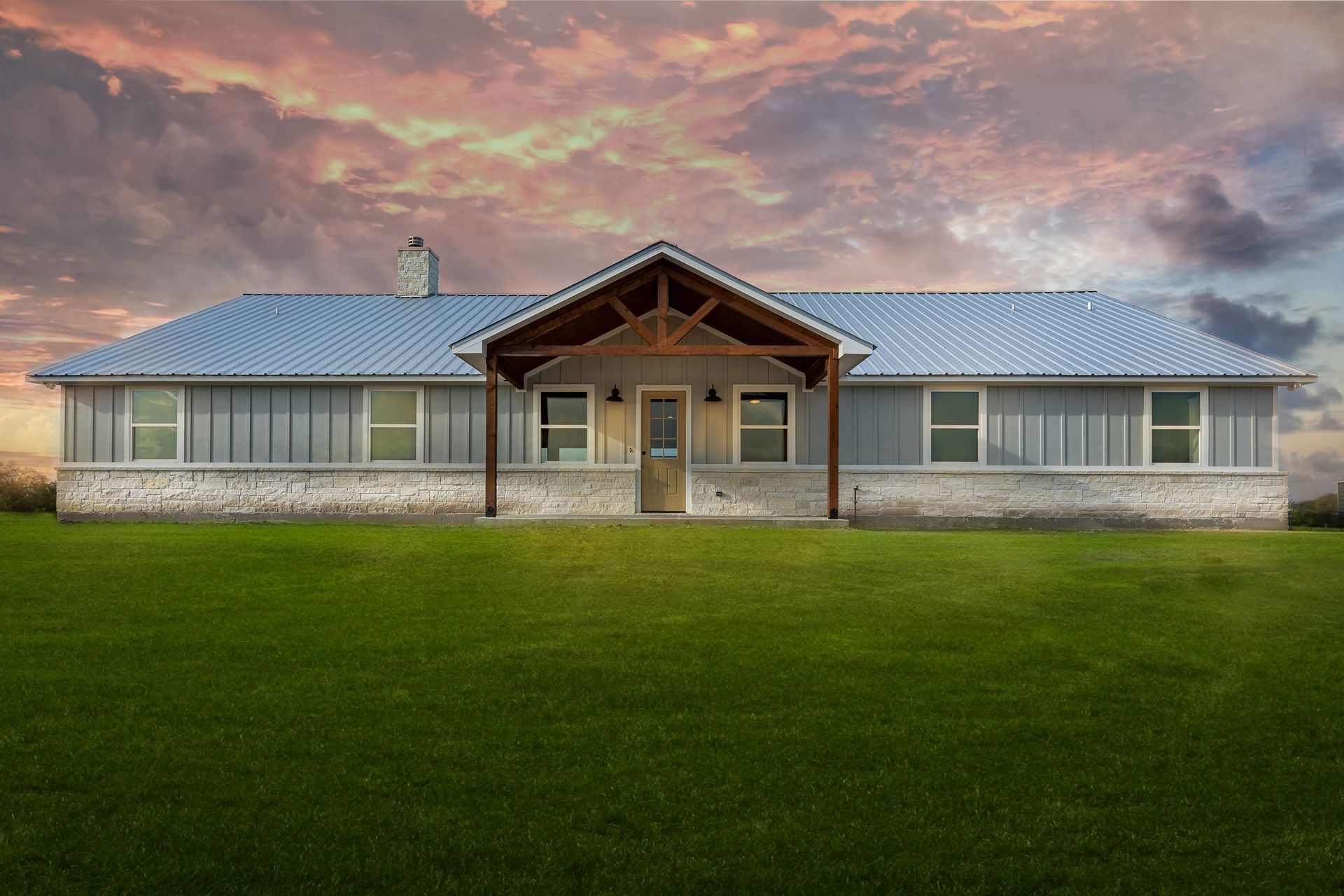 A large house with a metal roof is sitting on top of a lush green field.