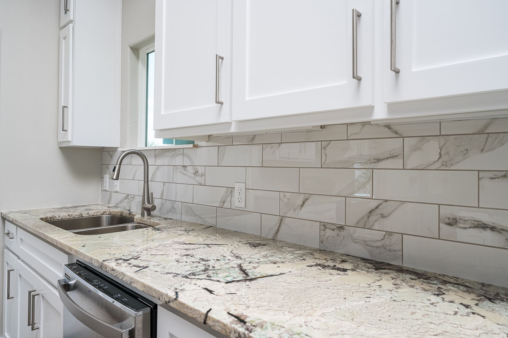 A kitchen with granite counter tops and white cabinets