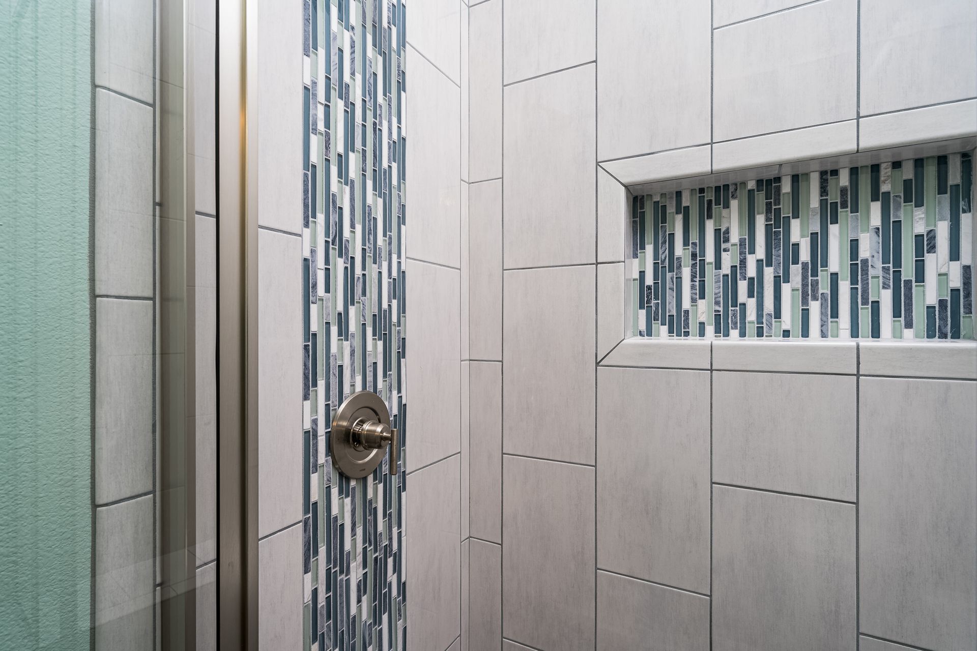 A bathroom with a walk in shower and a tiled wall.