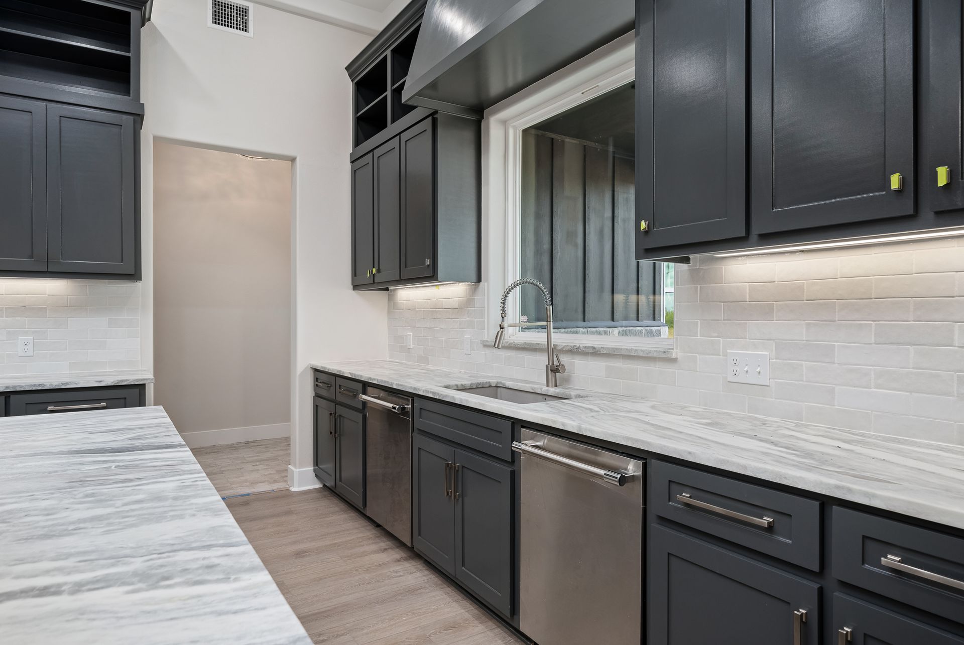 A kitchen with black cabinets , white counter tops , and stainless steel appliances.