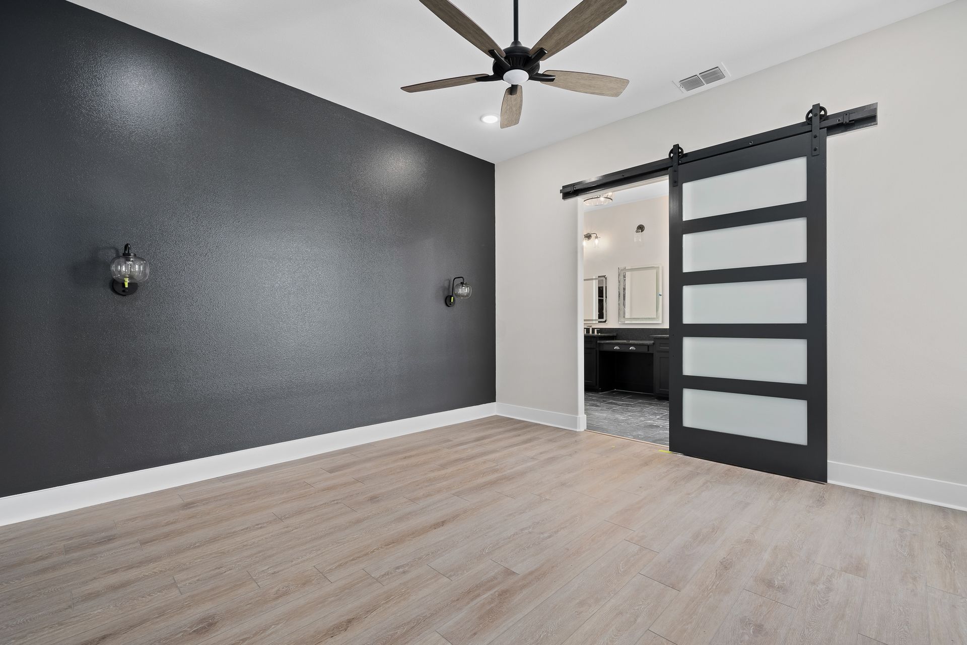 An empty room with a sliding barn door and a ceiling fan.