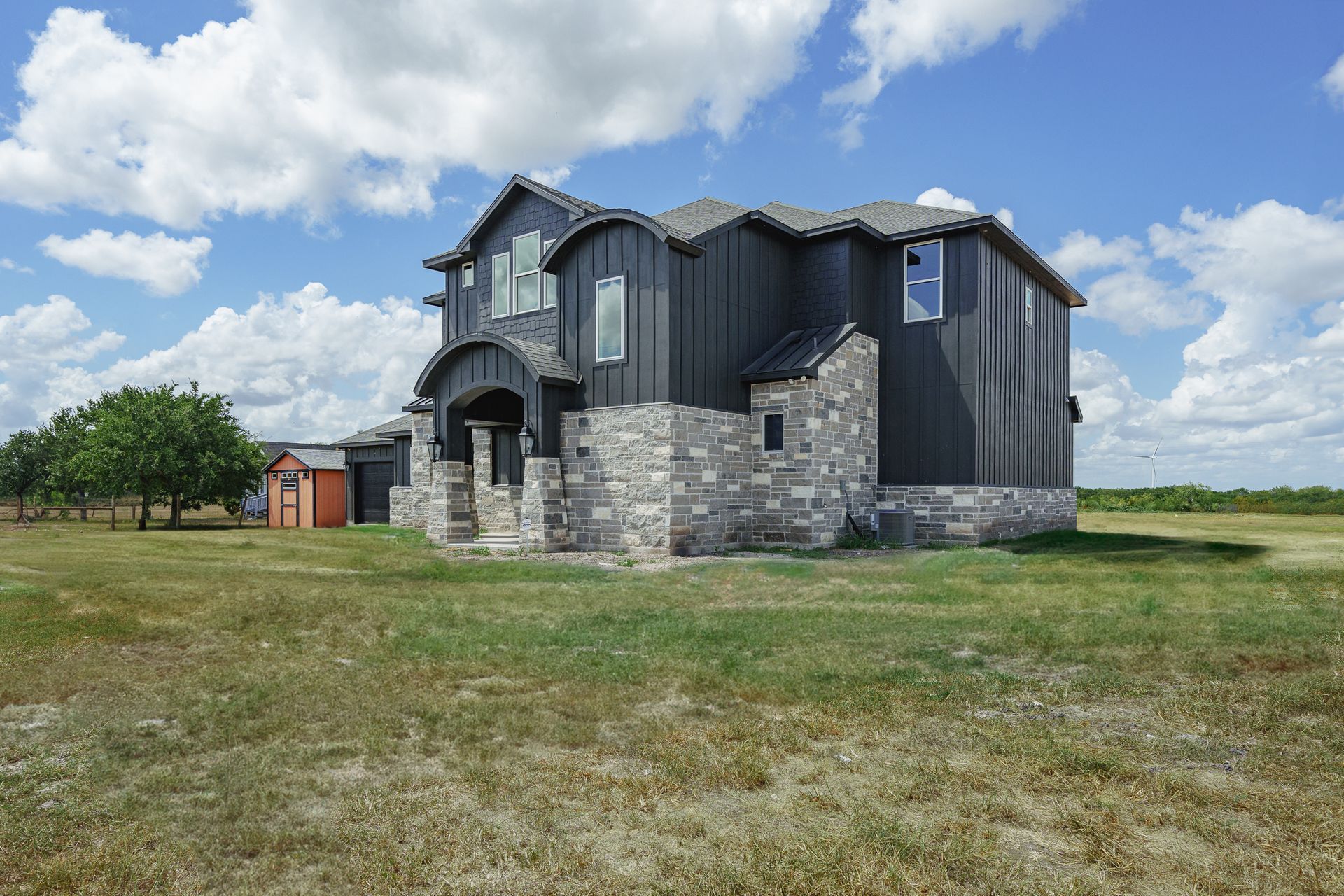 A large house is sitting in the middle of a grassy field.