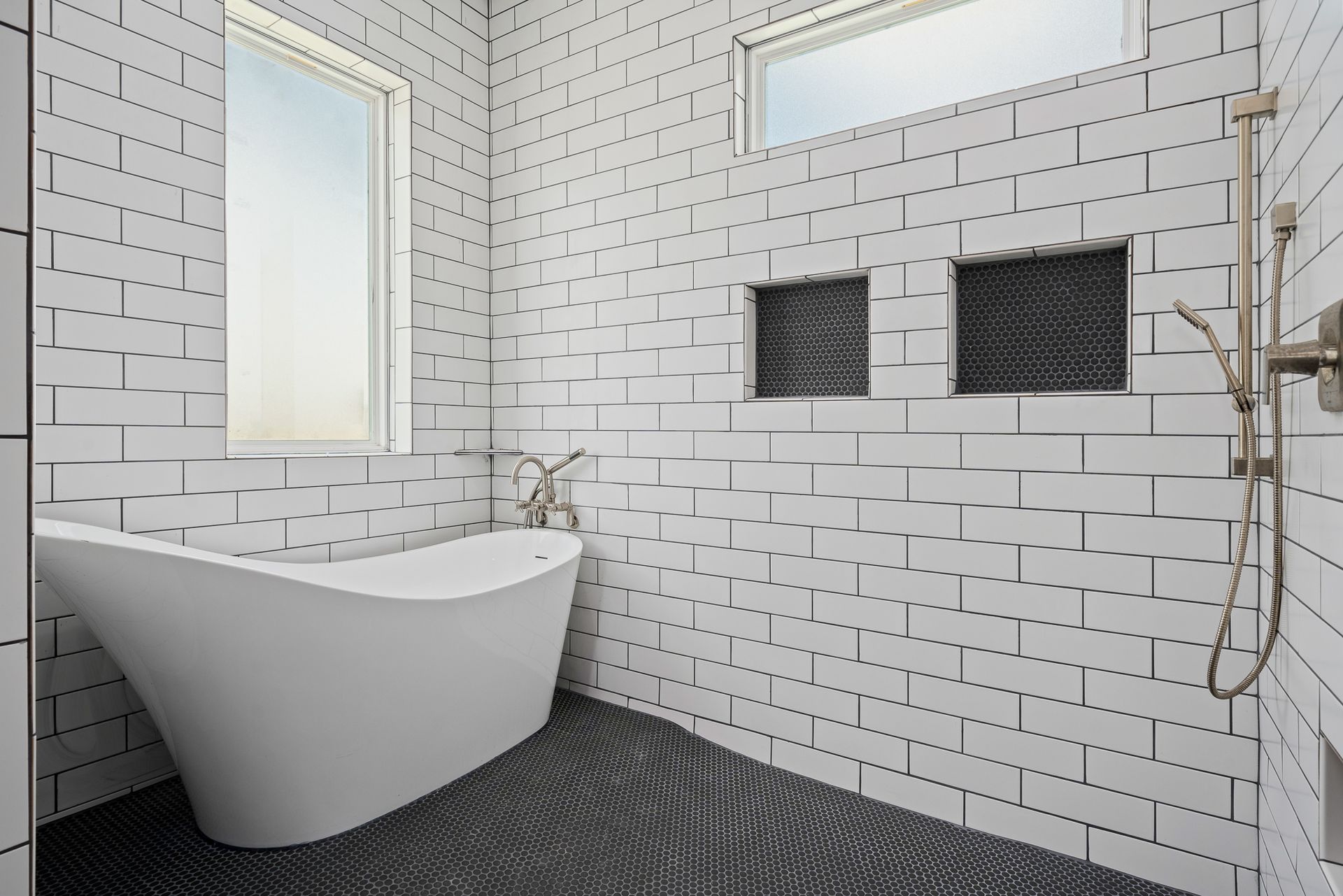 A bathroom with black and white tiles and a bathtub.