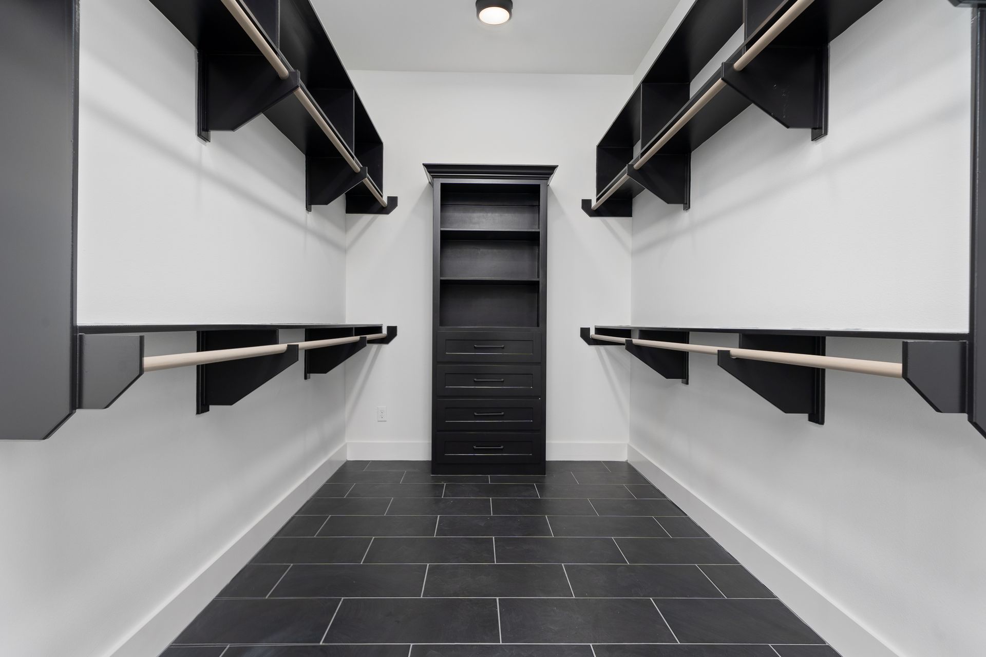 A walk in closet with black shelves and a black door