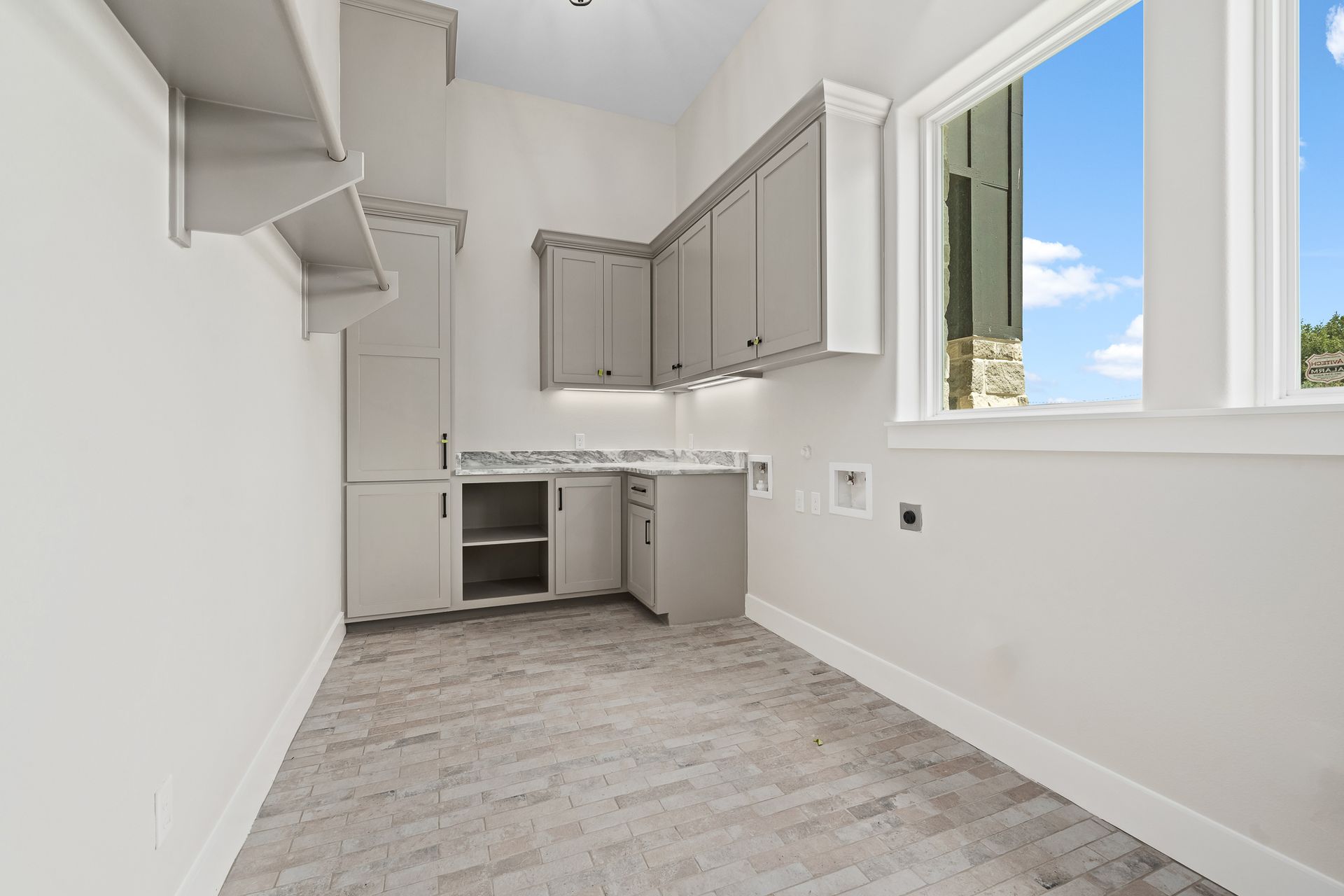 An empty kitchen with white cabinets and a window.
