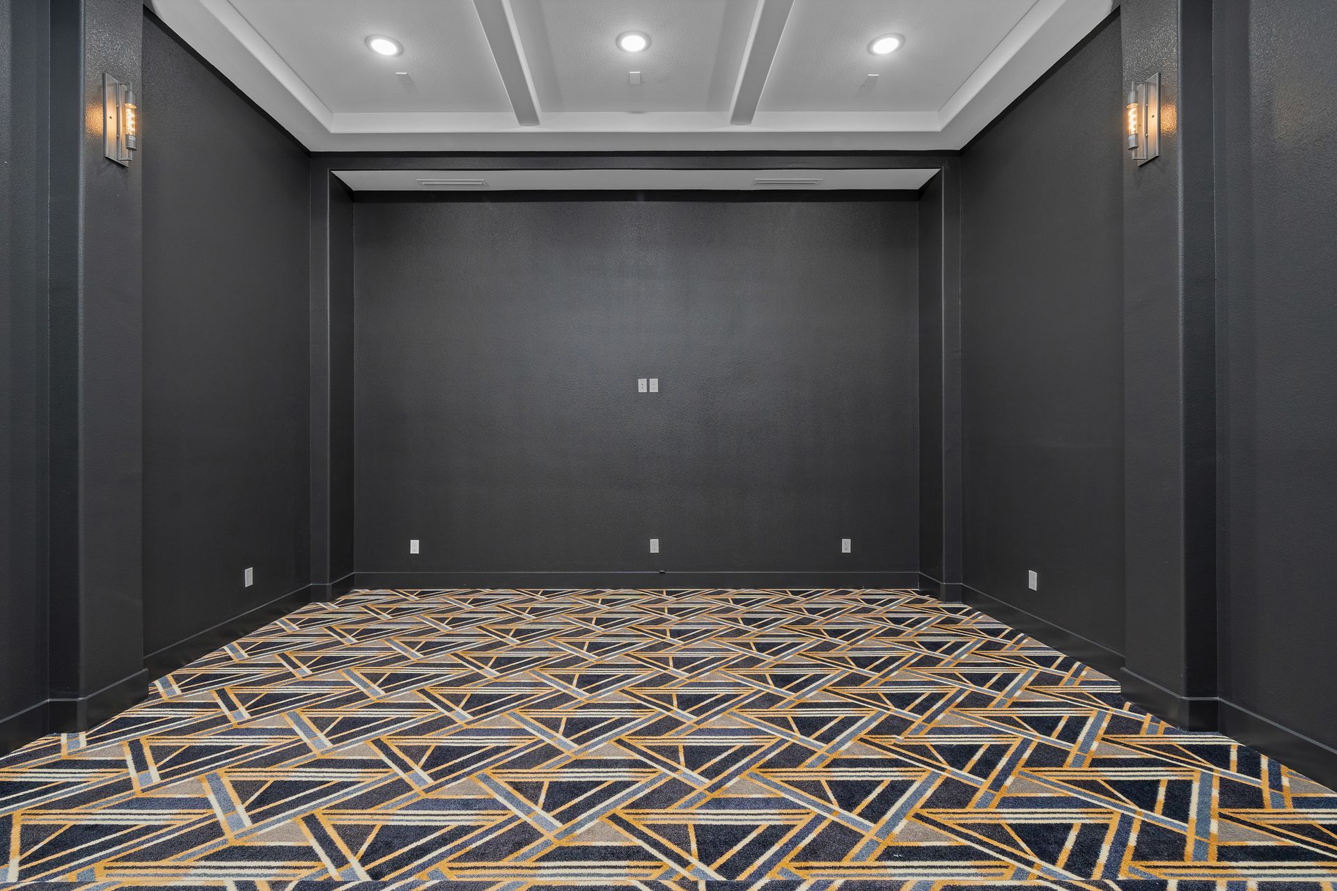 An empty room with a patterned carpet and black walls.